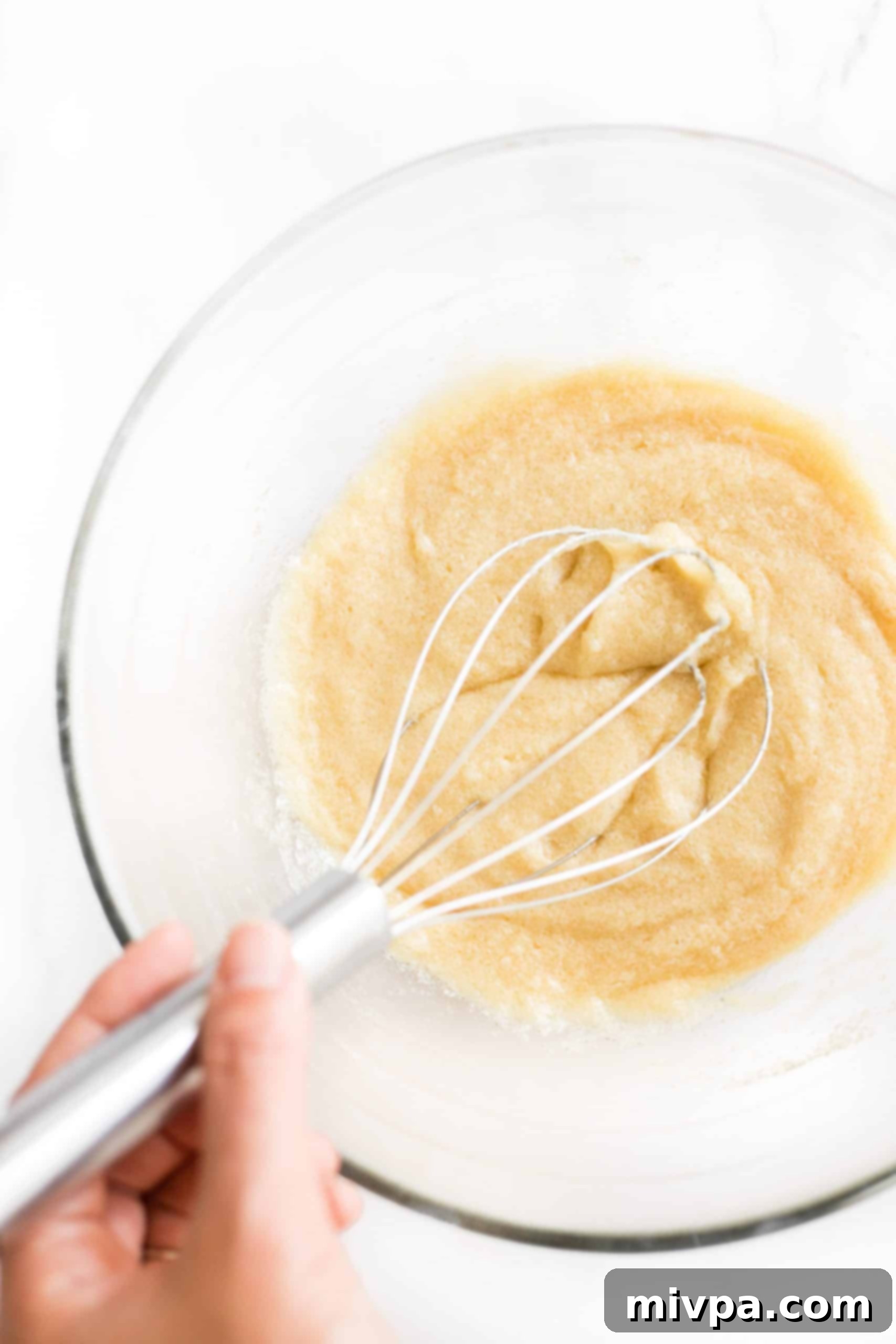 Whisking the wet ingredients including creamed sugar, coconut oil, egg, and vanilla extract in a large bowl to form a smooth snickerdoodle cookie dough base.