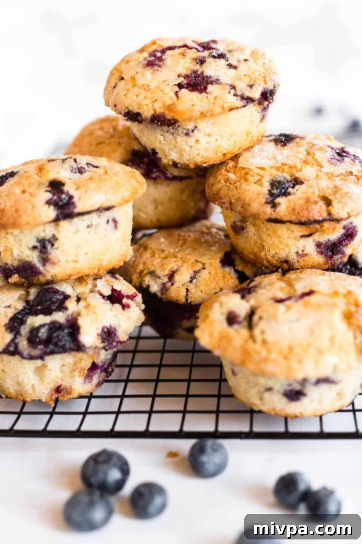 Gluten-free blueberry muffins stacked on wire rack.