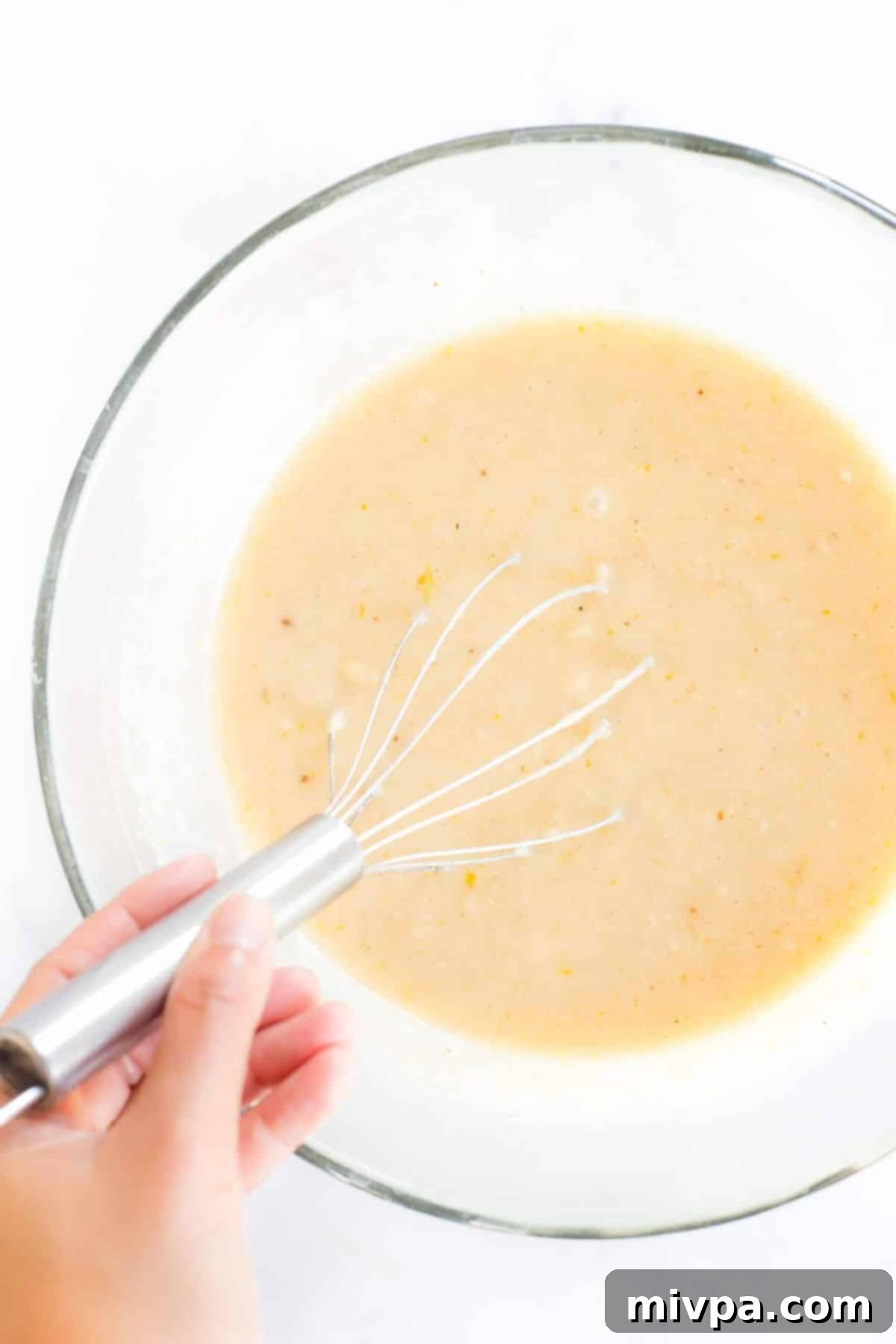 Whisking pale yellow mixture in glass bowl