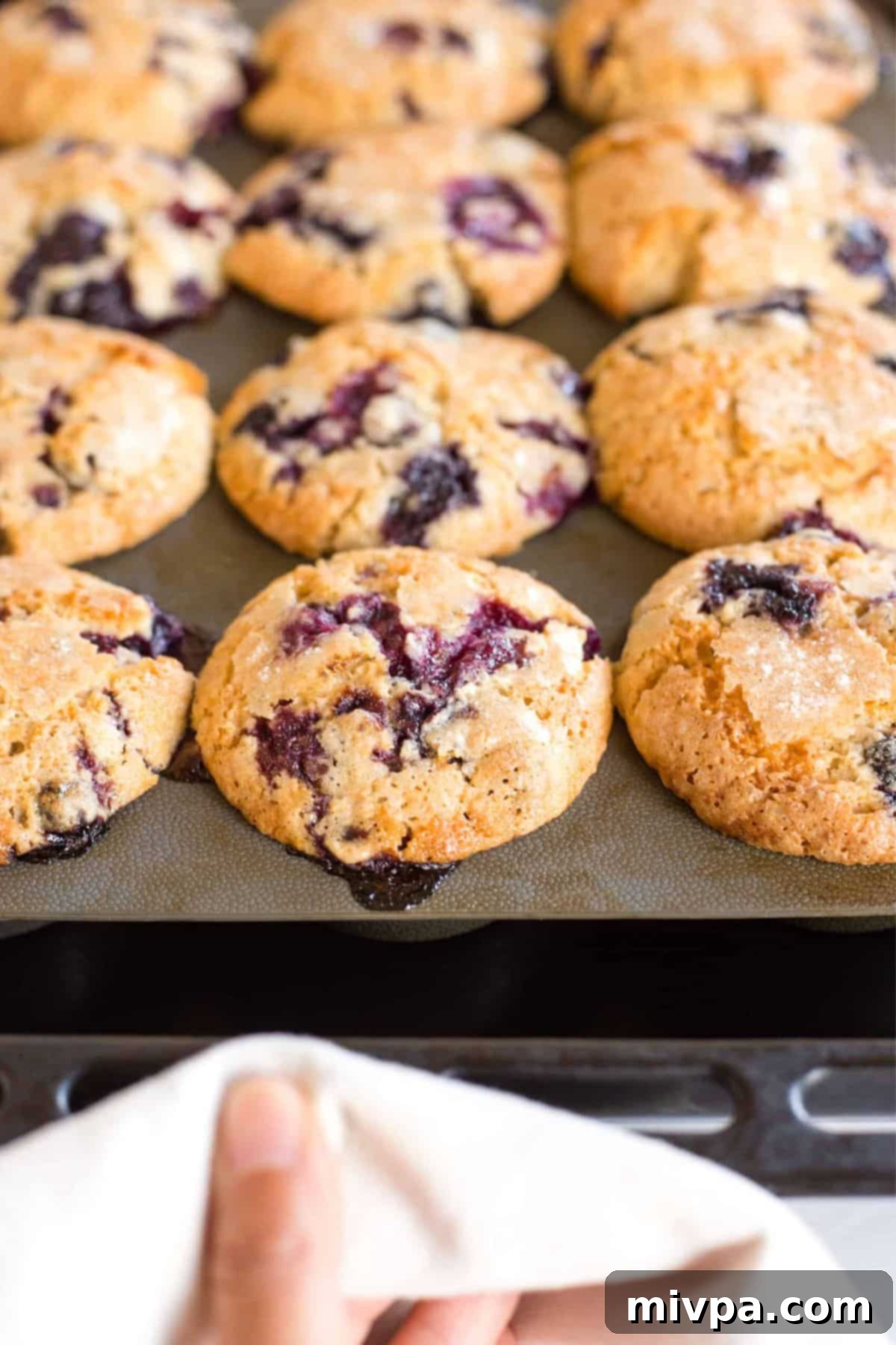 Pulling out a baking pan with freshly baked gluten-free muffins