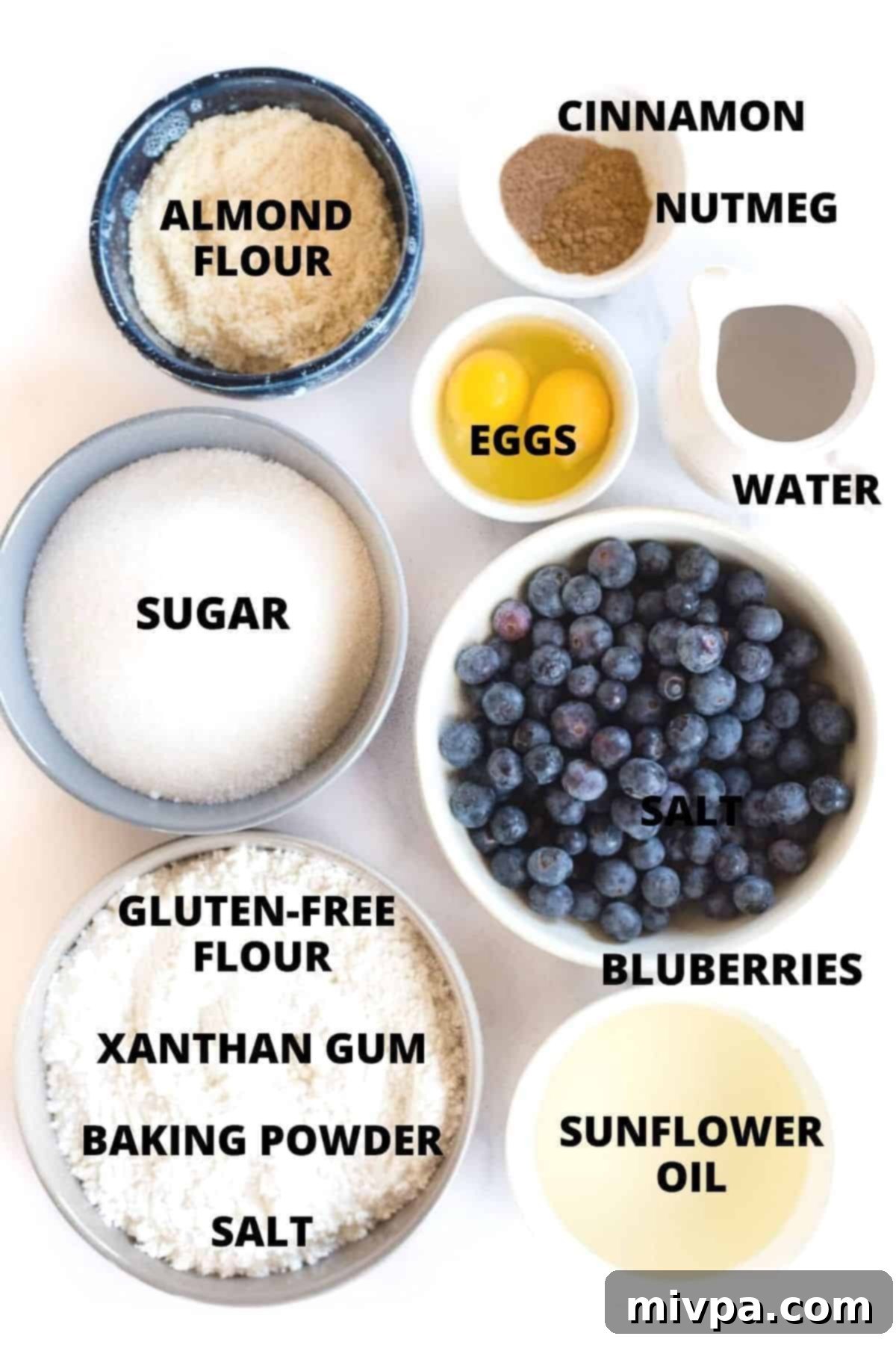 Ingredients for gluten-free blueberry muffin recipe laid out on white board.
