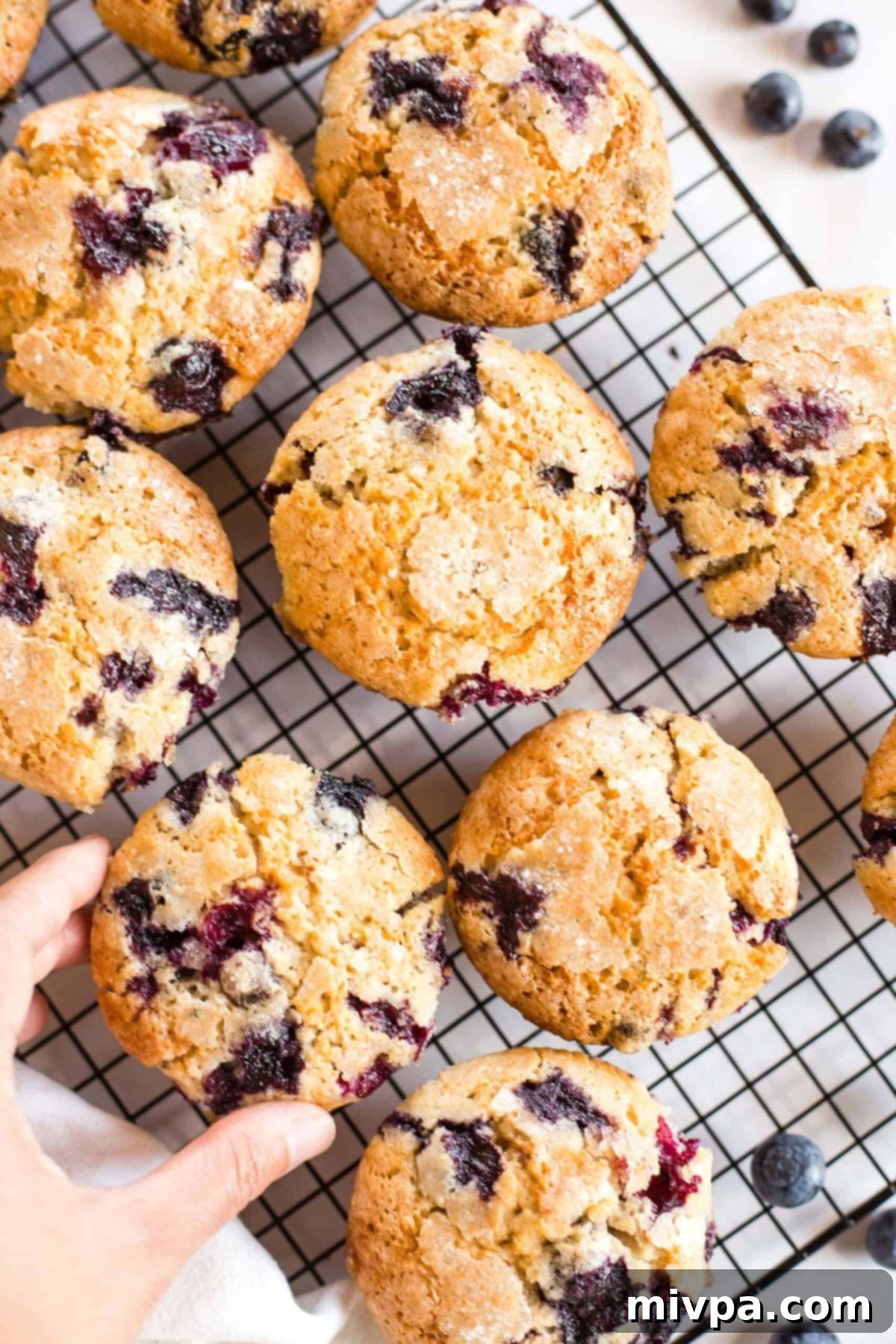 Reaching for GF DF blueberry muffins on wire rack.
