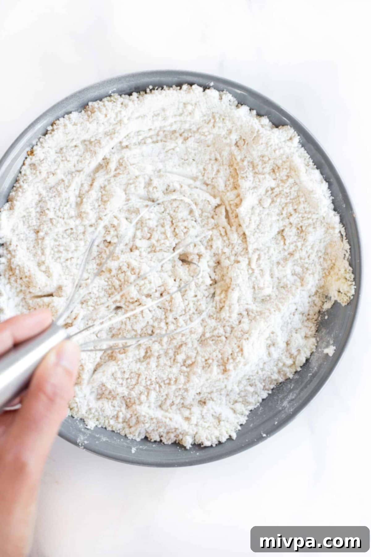 Whisking flour mixture in grey bowl.
