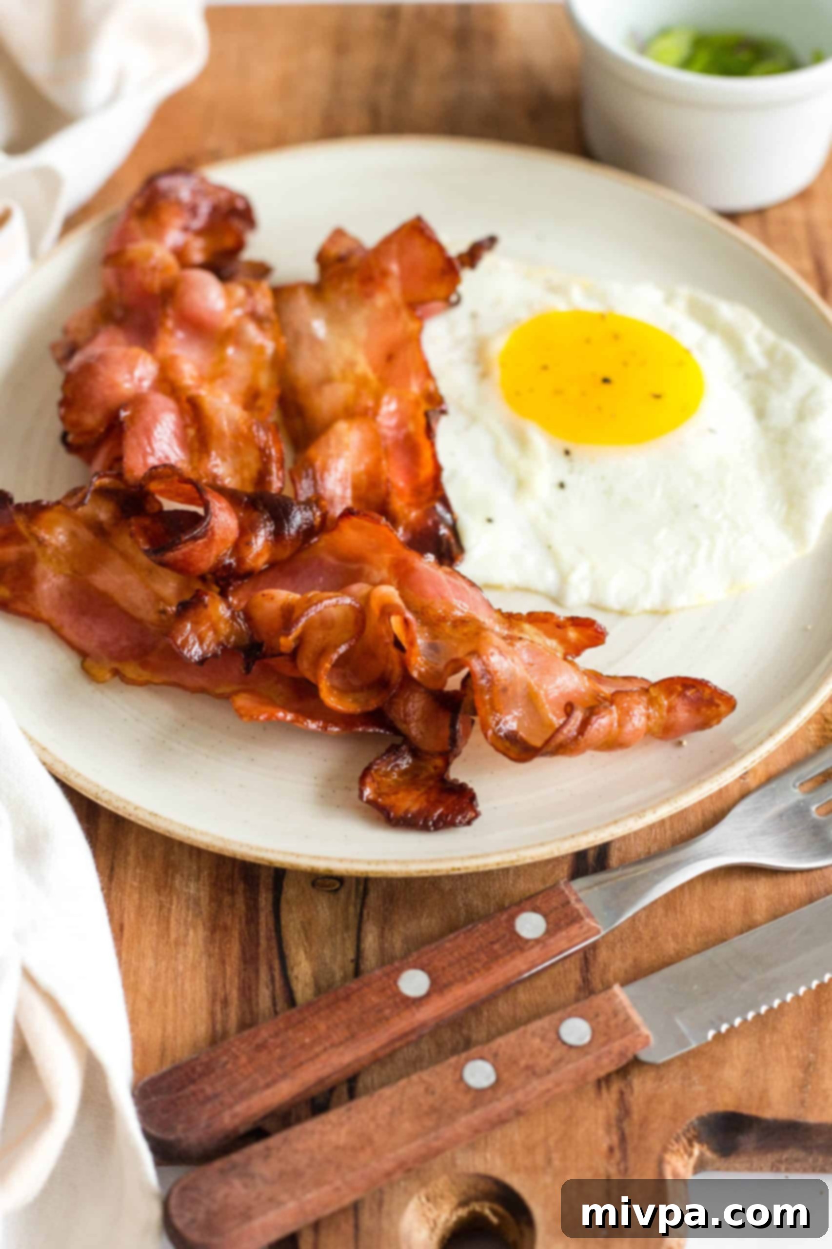 A beautifully arranged plate of air fried bacon and eggs, served on a rustic wooden board.