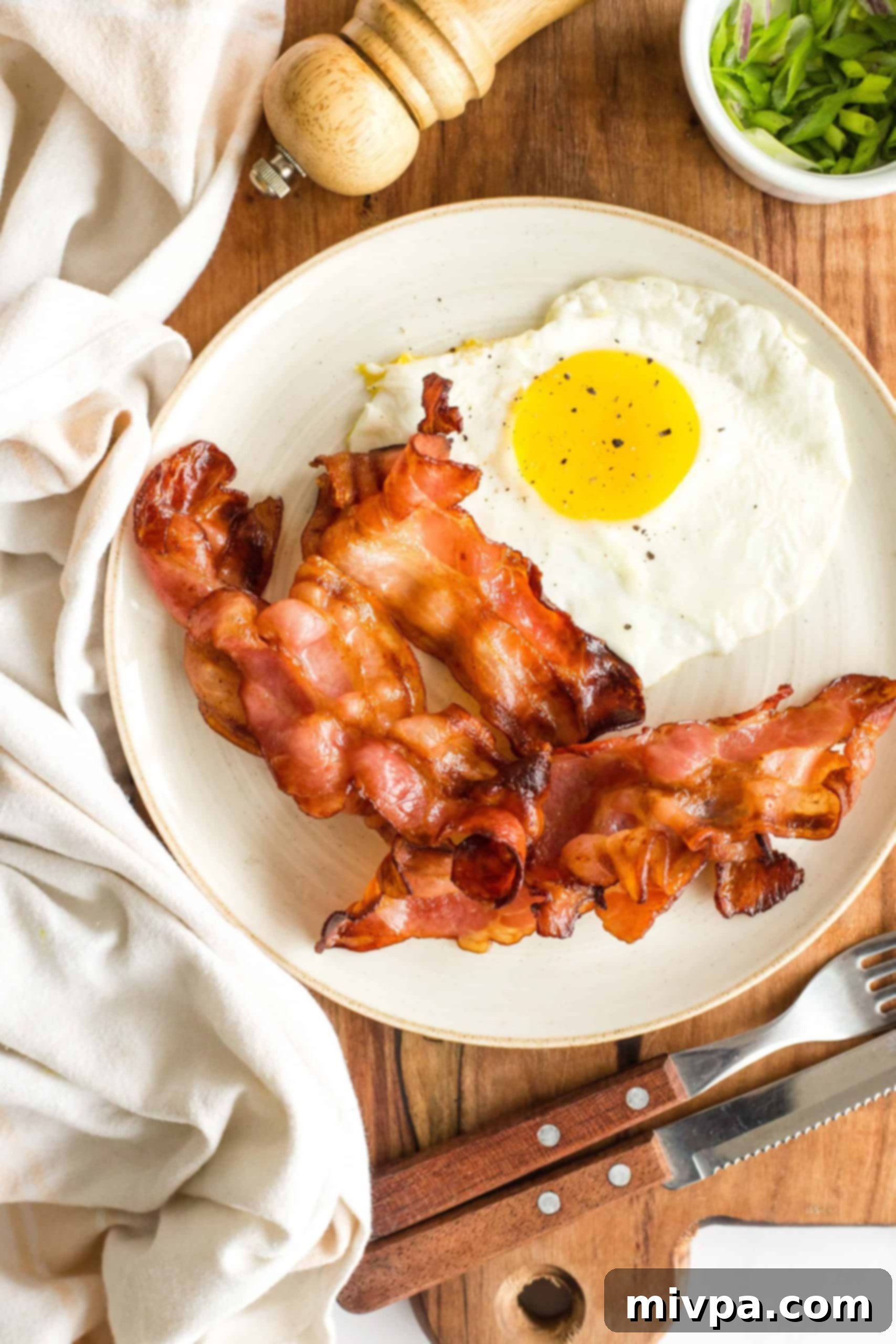 Crispy air fried bacon and eggs on a plate, ready to be enjoyed on a wooden board.