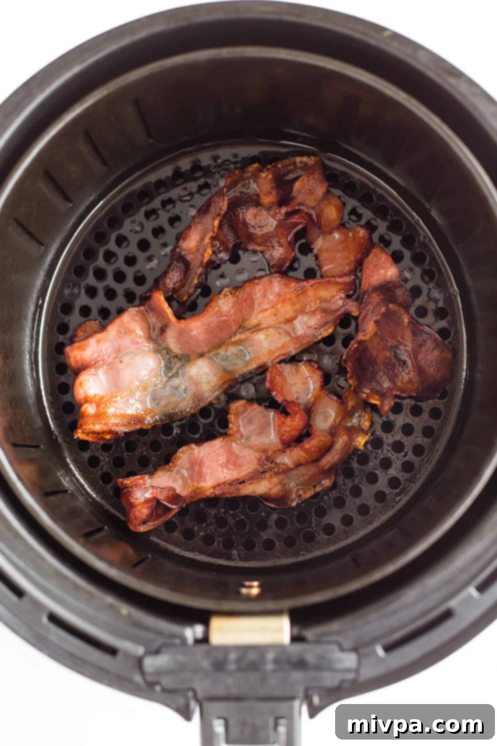 Crispy air fryer bacon slices, golden brown and perfectly cooked, resting inside the air fryer basket.