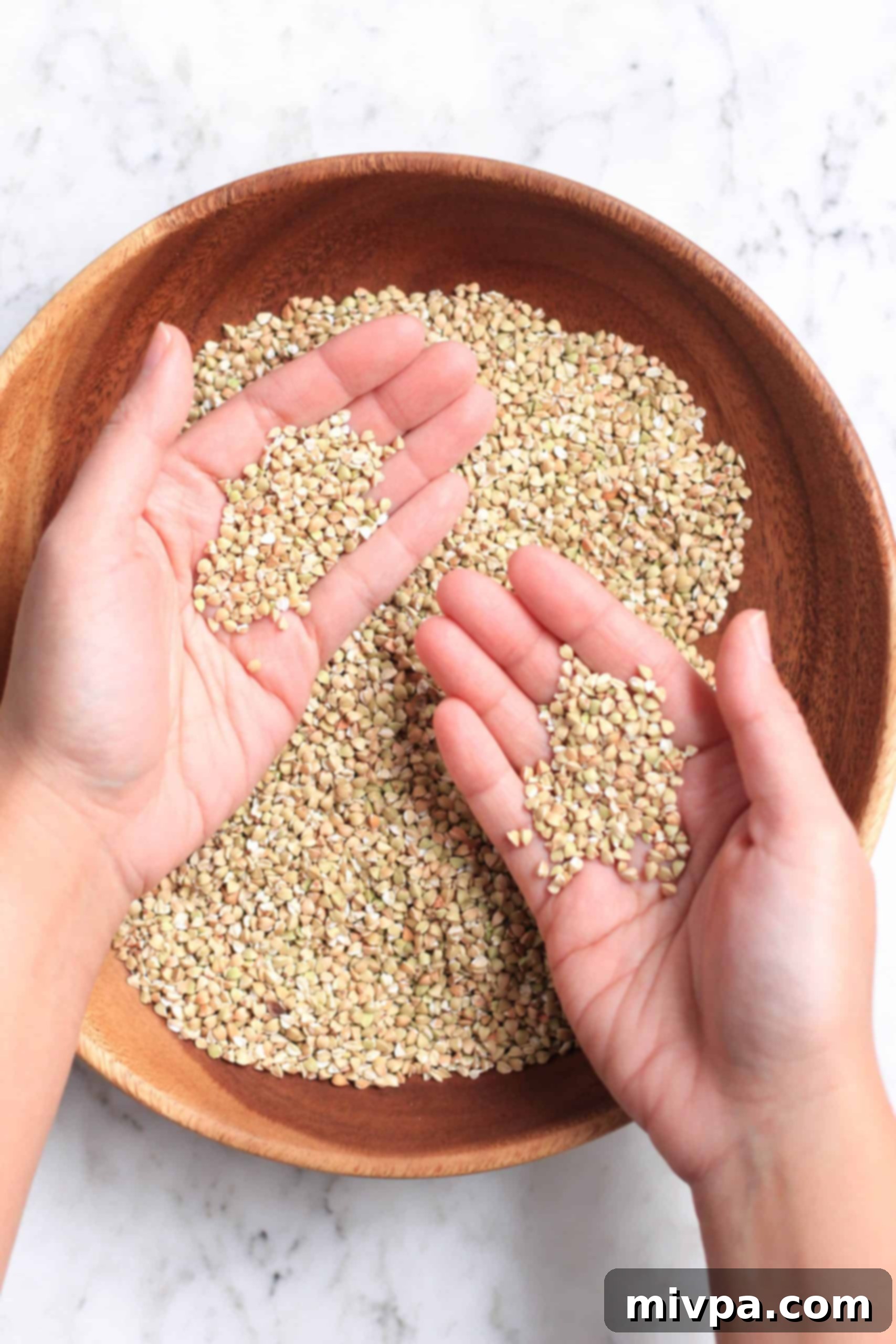 How to Make Buckwheat Flour (Gluten-Free, Vegan) Holding up handfuls of raw buckwheat groats.