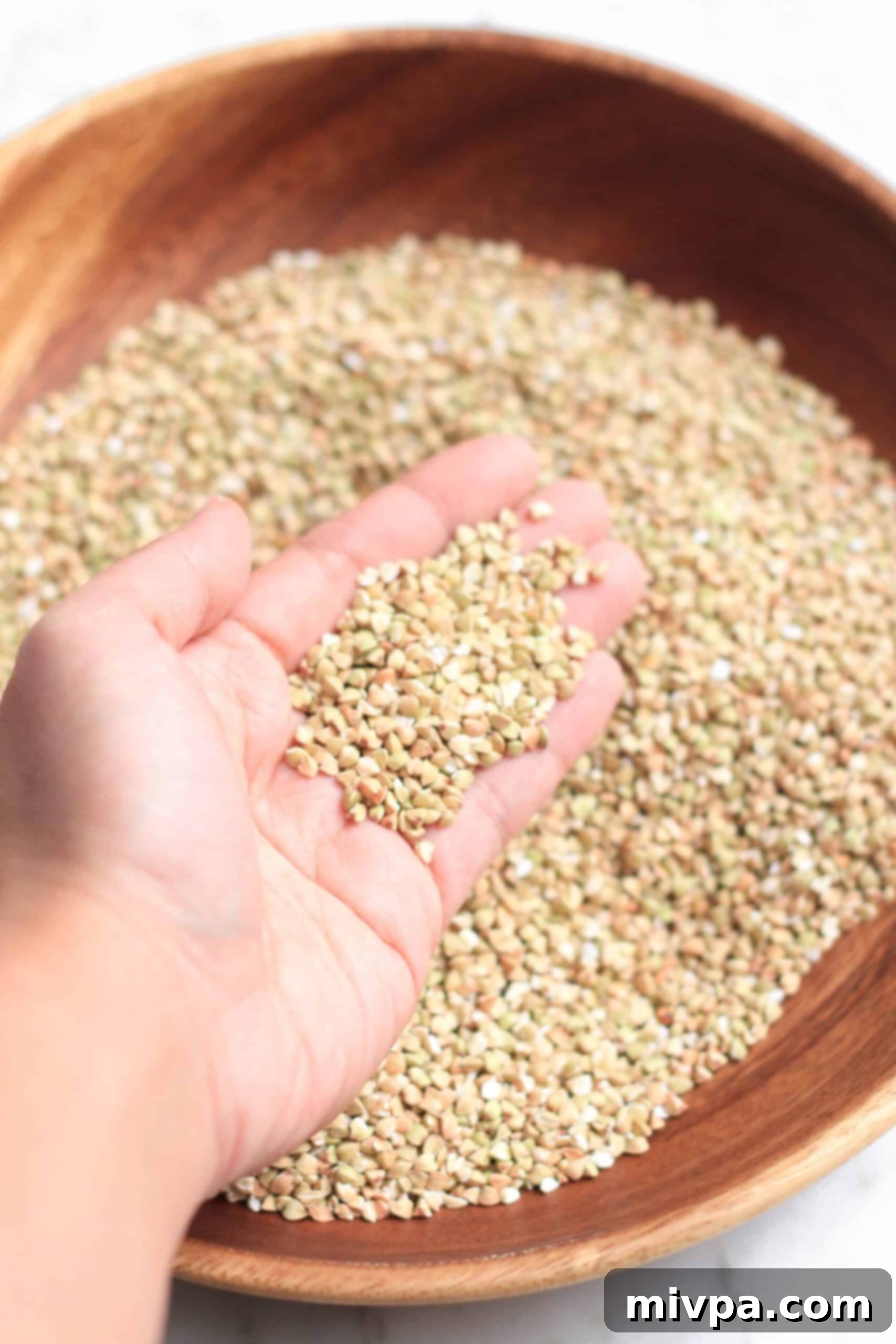 5-Minute Homemade Buckwheat Flour (Gluten-Free, Vegan) Holding up a handful of hulled buckwheat groats.
