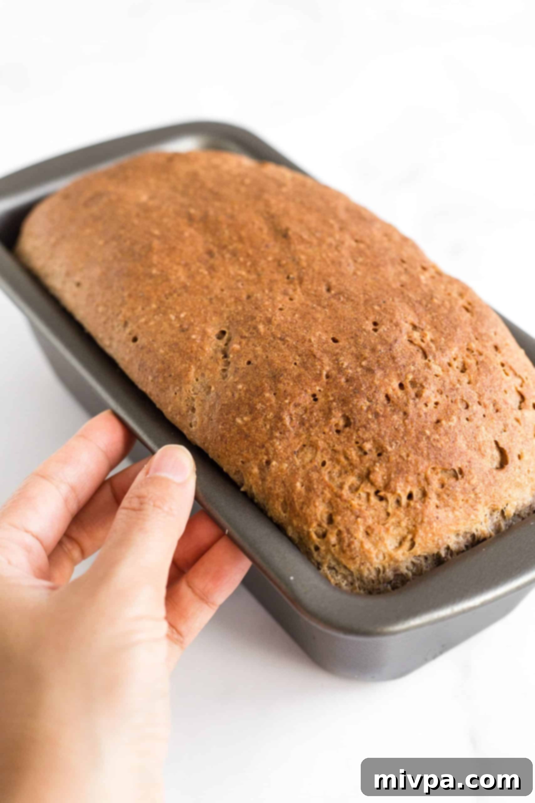 Holding a pan with a freshly baked loaf of bread.