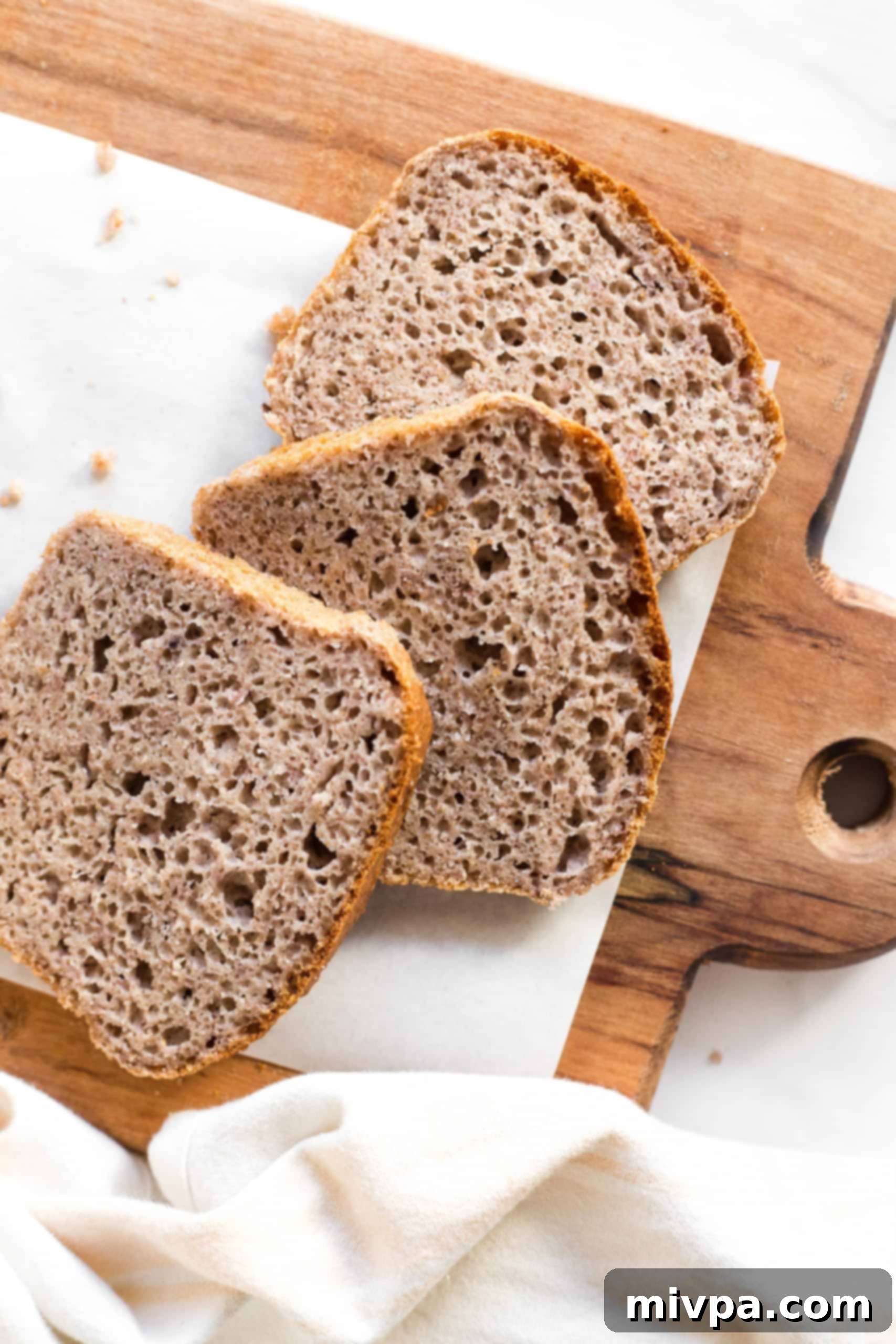 Three slices of brown bread on a wooden board.