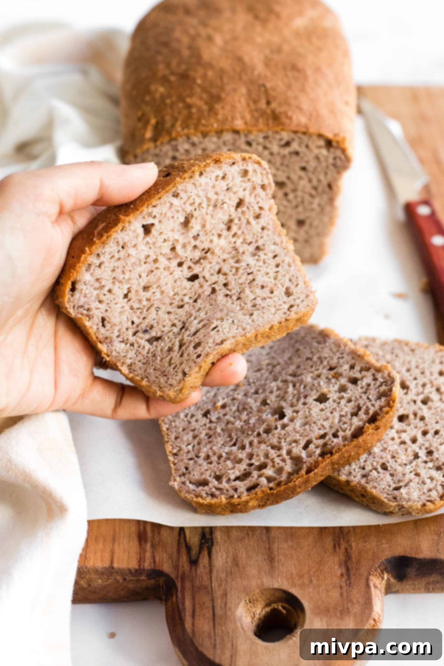 Hand squishing a slice of gluten-free brown bread.