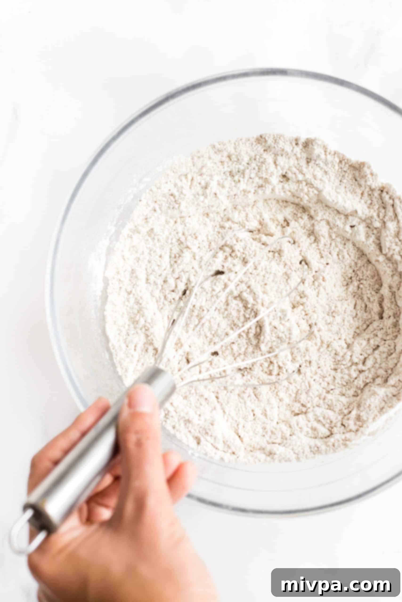 Mixing dry ingredients in a glass bowl.