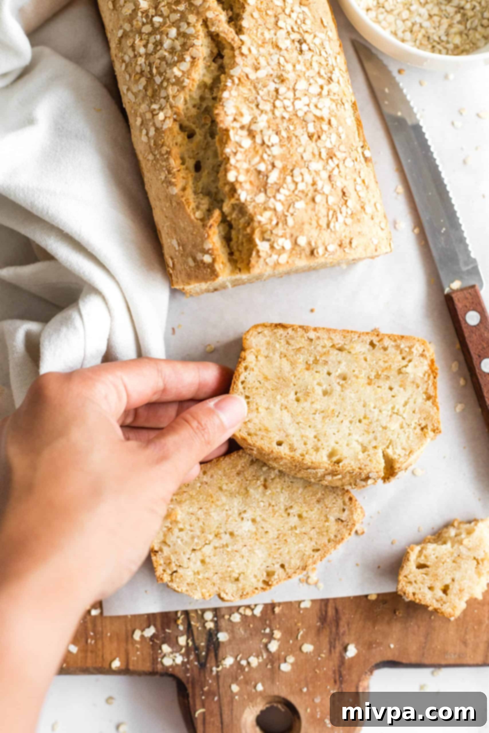 Hand reaching for a slice of quinoa quick bread.