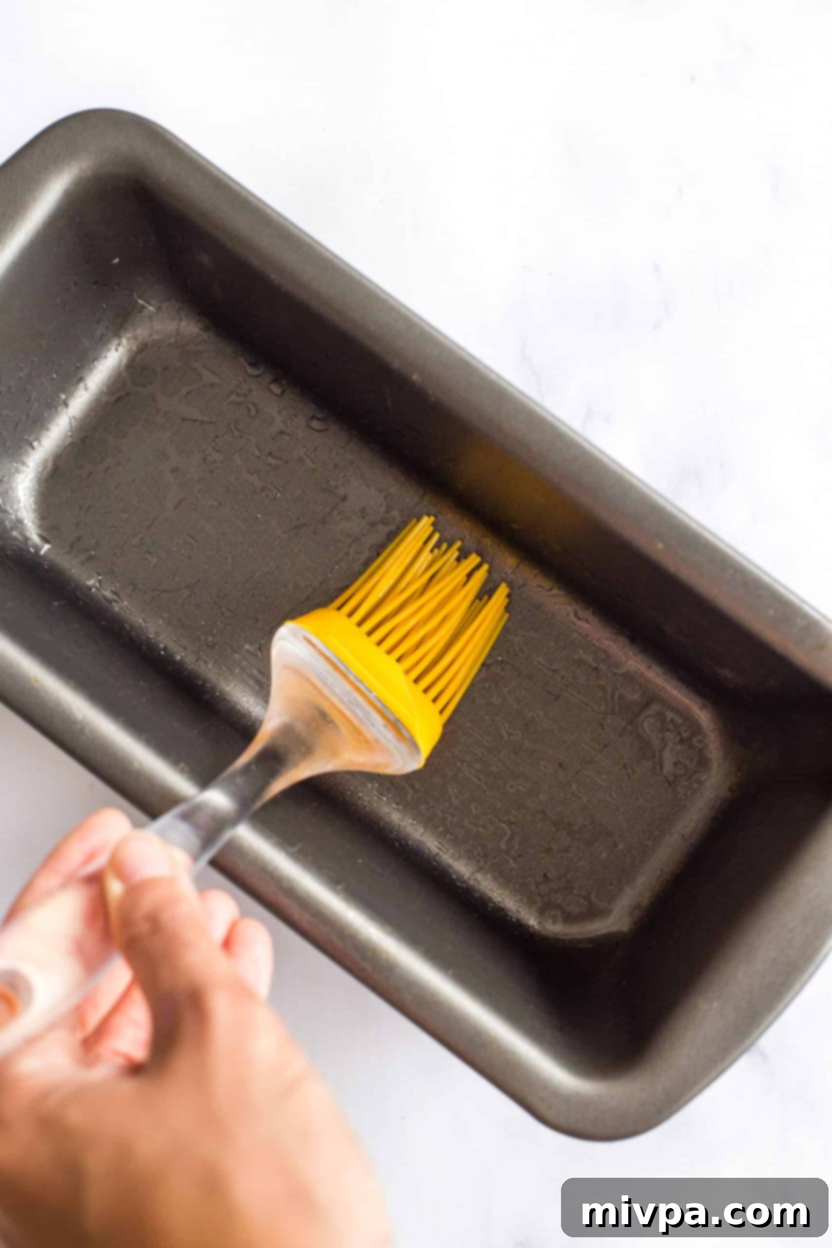 Greasing a metal loaf pan.
