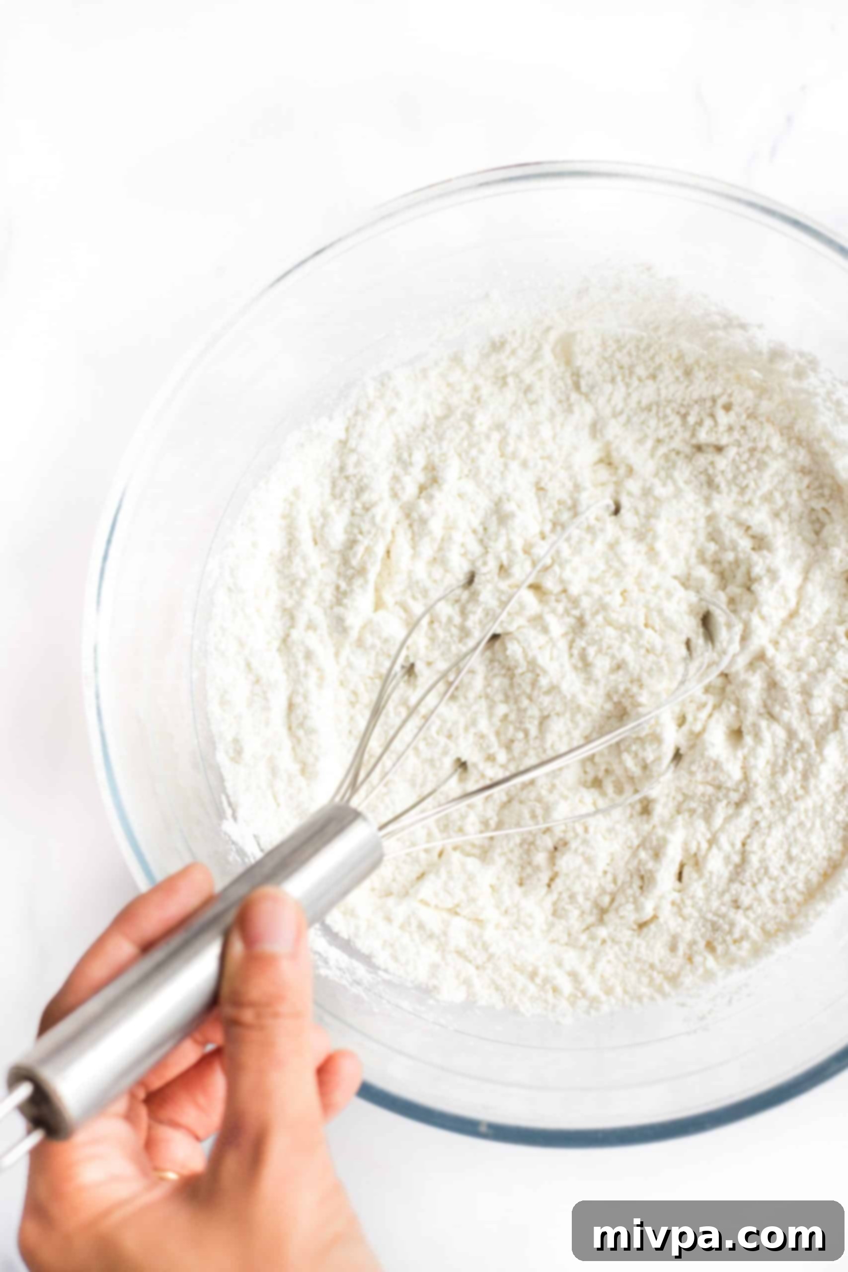 Whisking dry ingredients in a glass bowl.