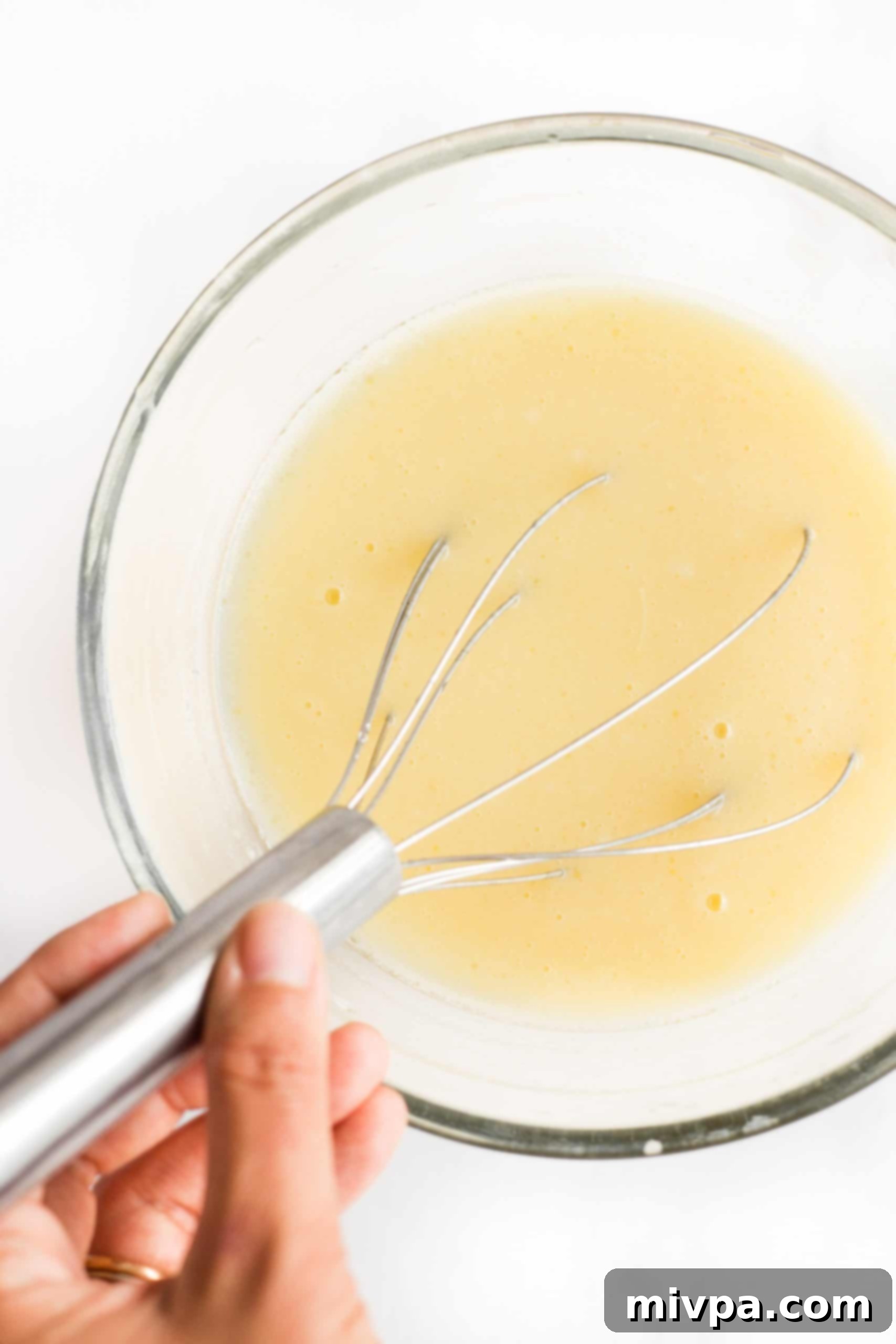 Whisking a liquid mixture in a glass bowl.