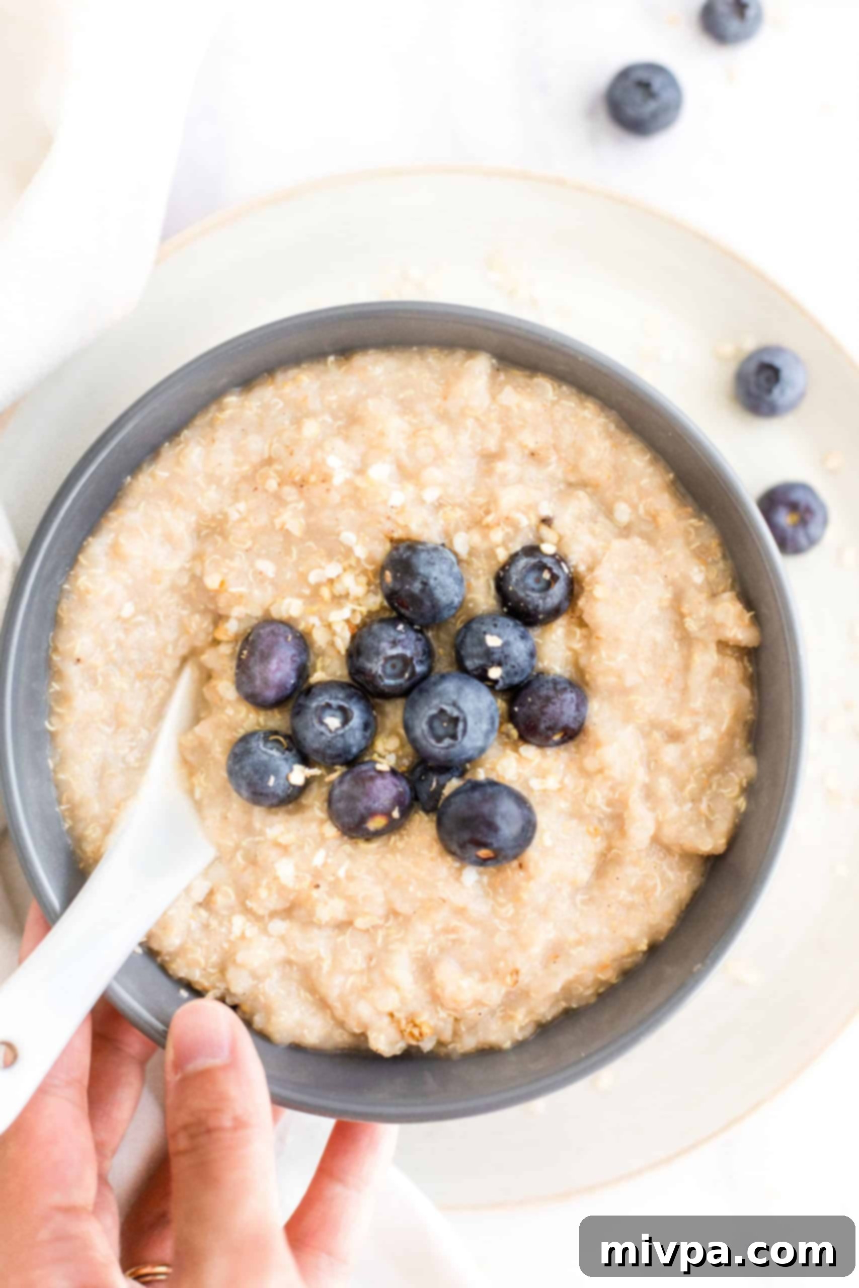 A bowl of creamy quinoa porridge with fresh blueberries and a sprinkle of quinoa flakes, ready to be enjoyed as a healthy breakfast.