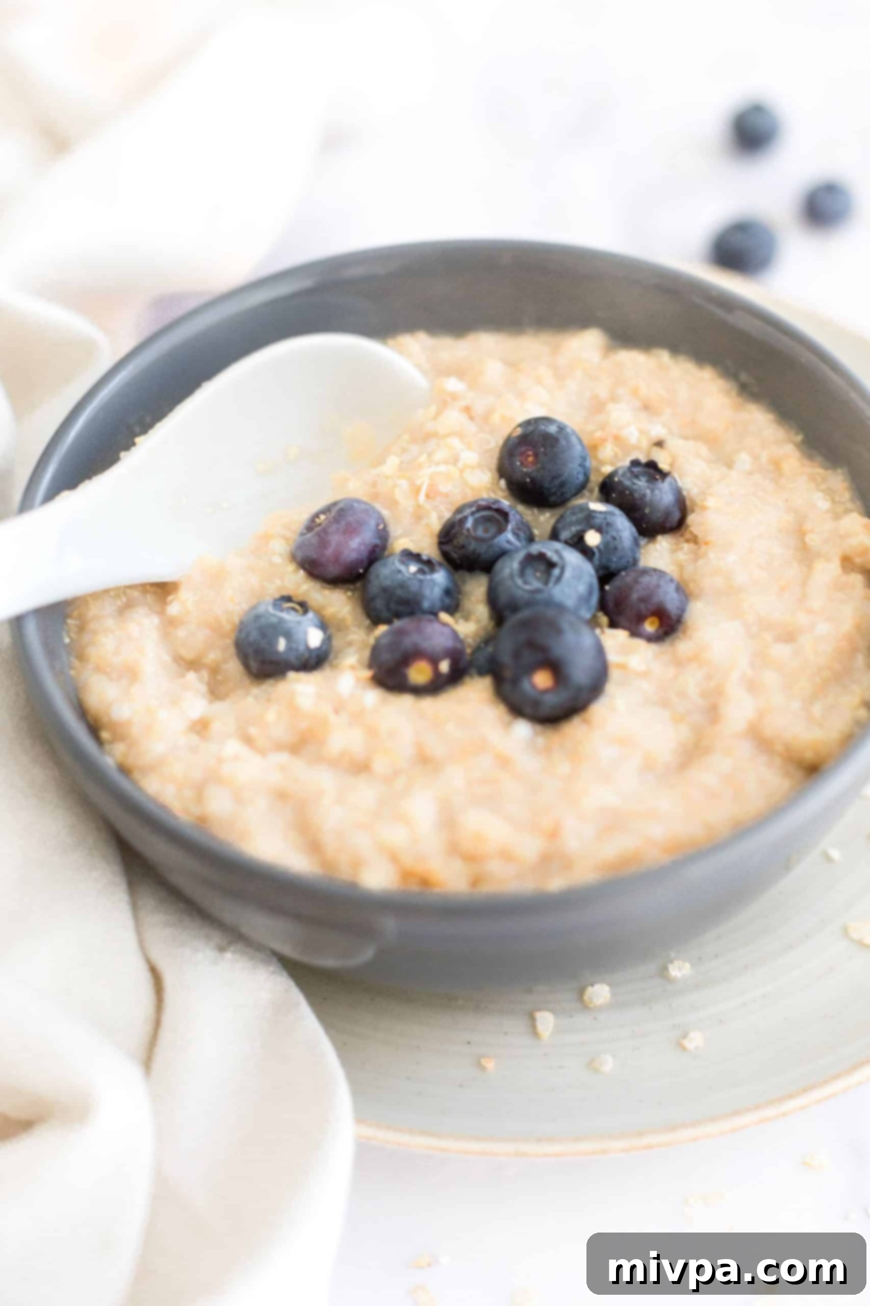 Close-up shot of creamy quinoa porridge in a grey bowl, highlighting its texture and inviting warmth.