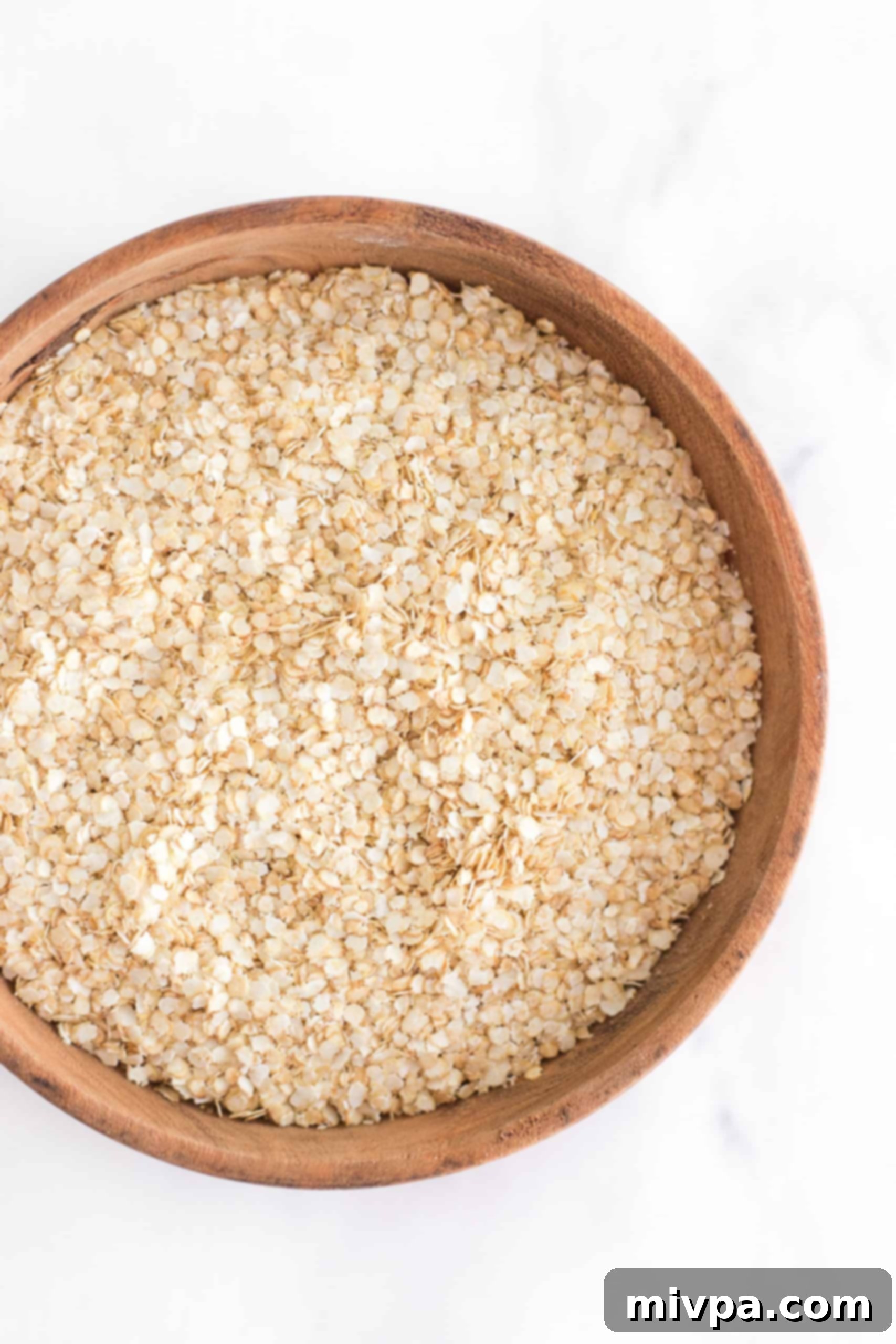 Close-up of quinoa flakes in a rustic wooden bowl, emphasizing their texture and readiness for cooking.