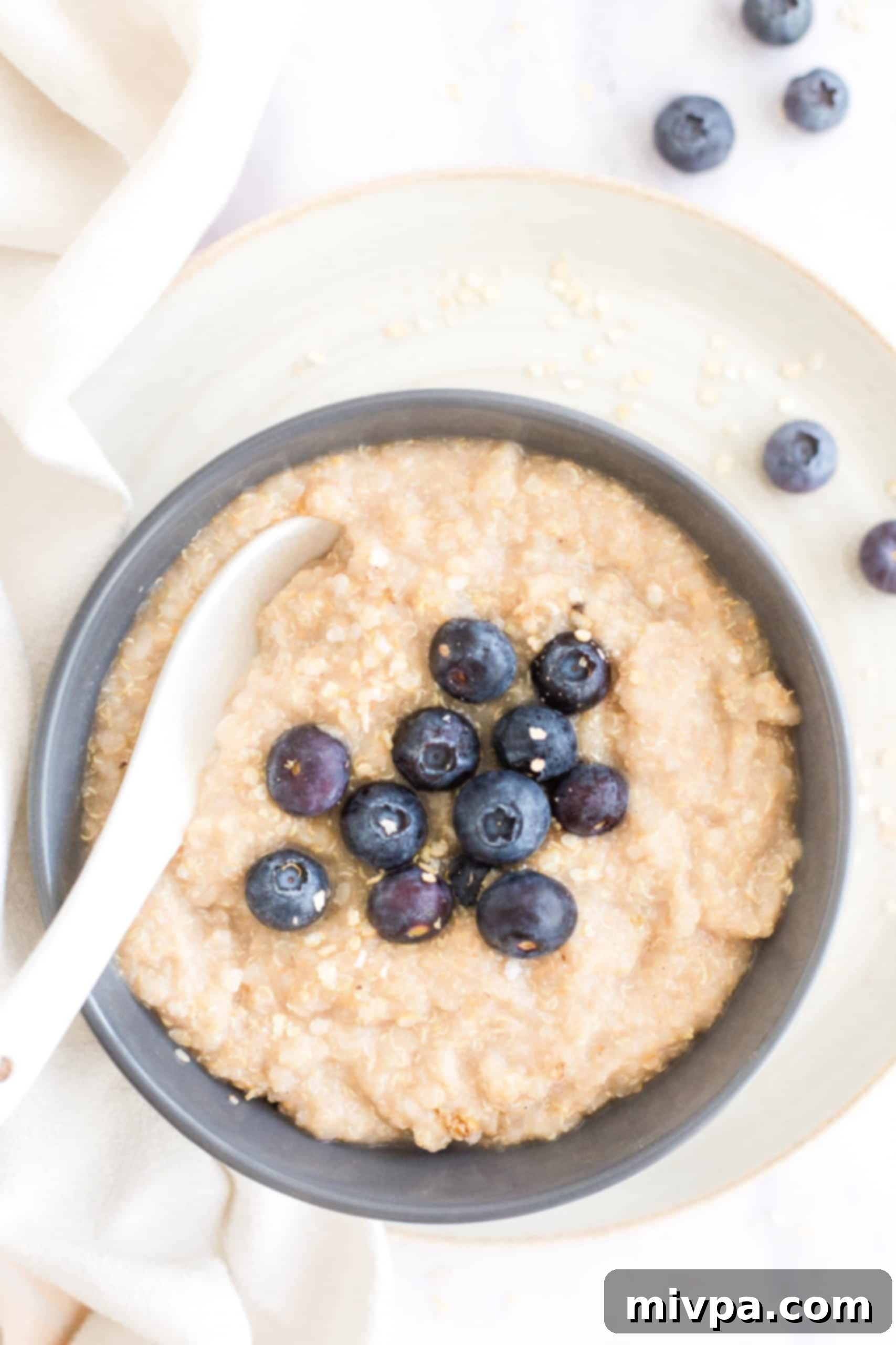 A large bowl of creamy quinoa porridge generously topped with fresh blueberries, ready to be served as a delightful breakfast.
