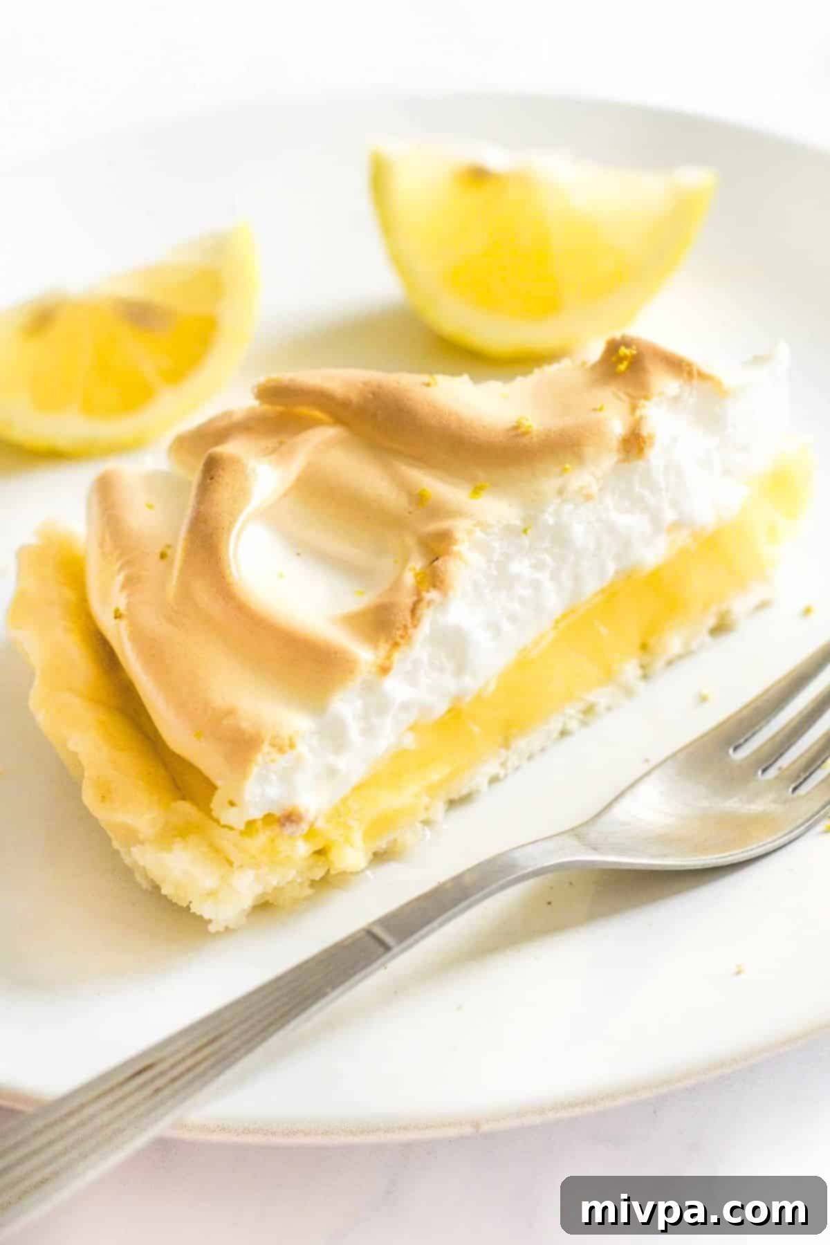 Up close shot of a slice of gluten-free lemon meringue pie on plate.