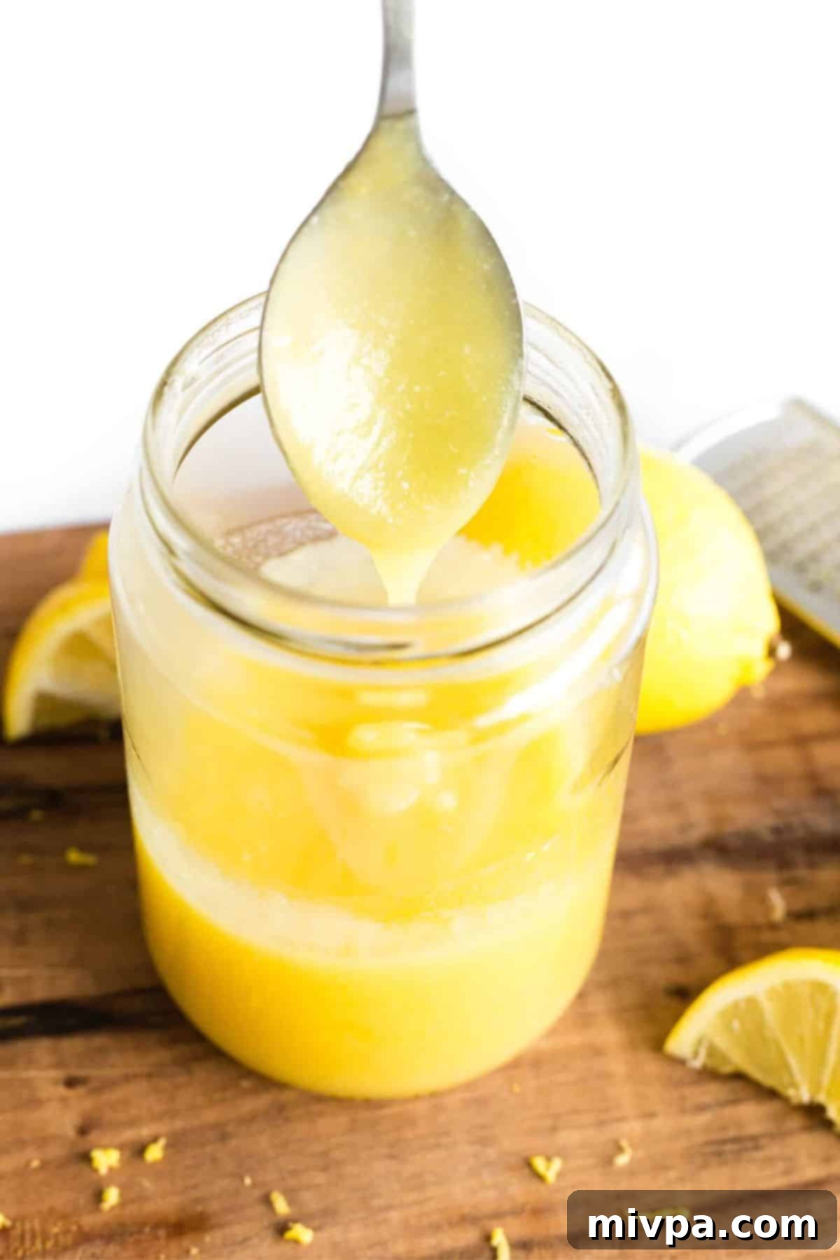Holding up a spoonful of lemon curd from a jar.