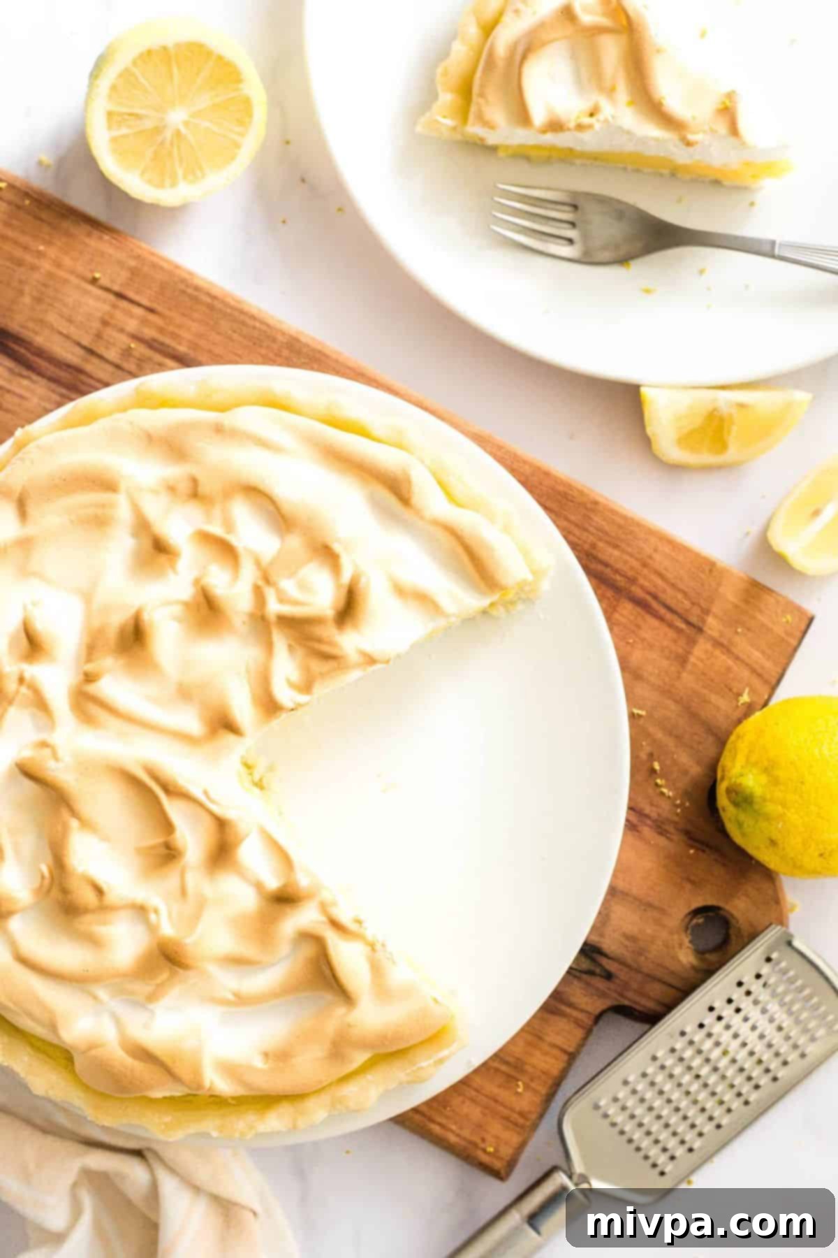 Top down view of half-eaten gf lemon pie on wooden board.