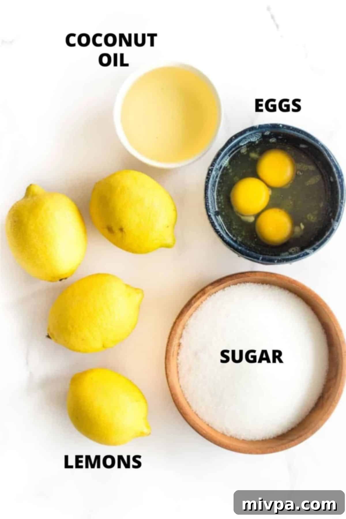 Top down view of ingredients for lemon curd laid out on white board.