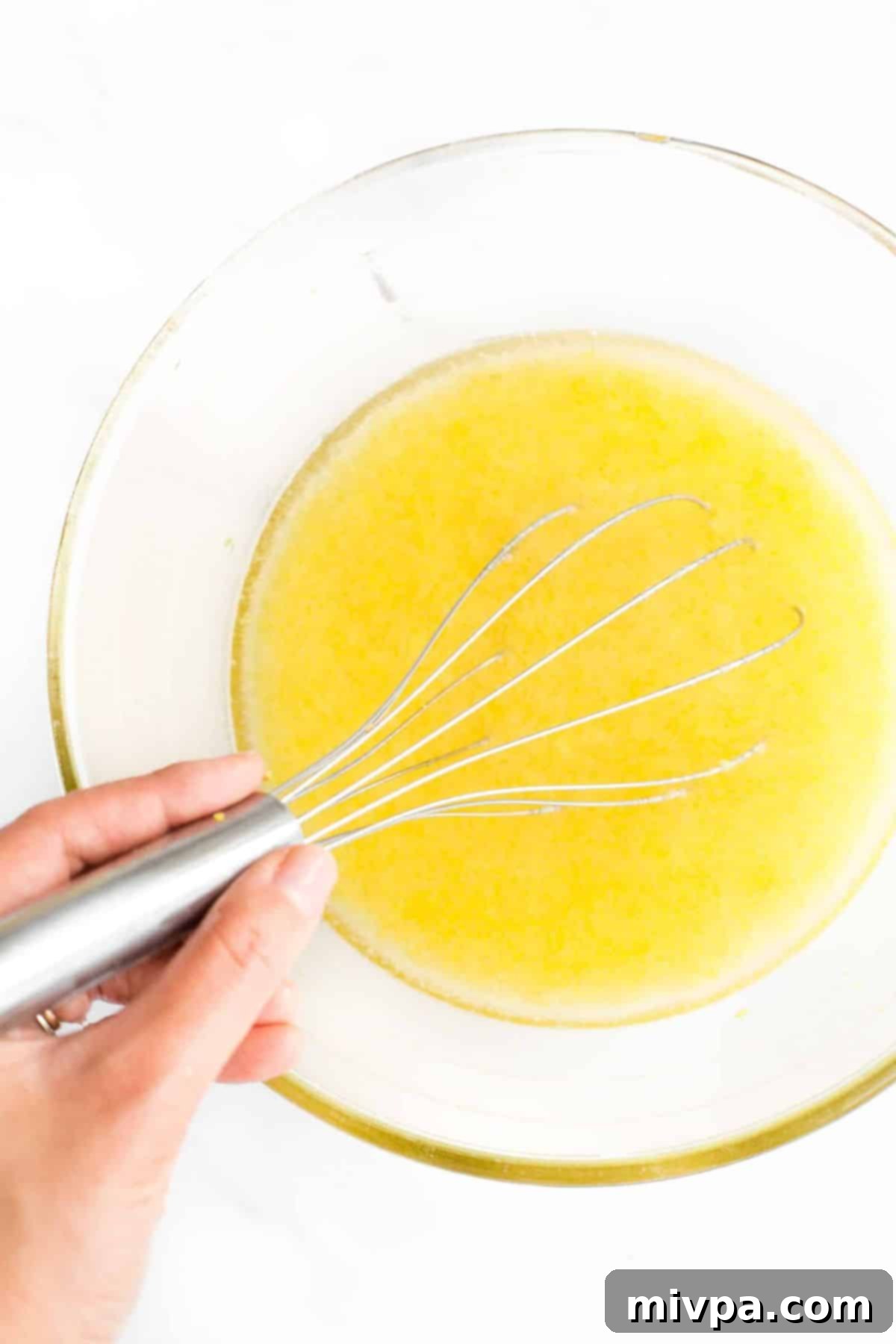 Whisking yellow liquid mixture with whisk.