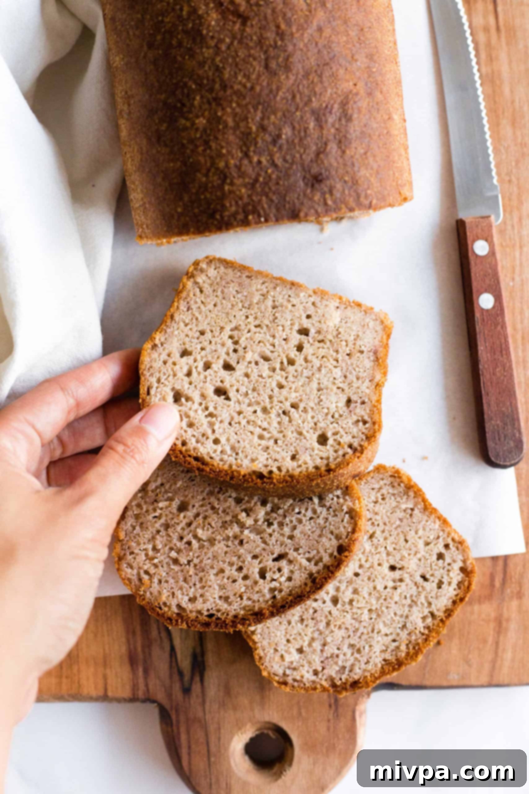 Hand reaching for a slice of freshly baked brown rice bread.