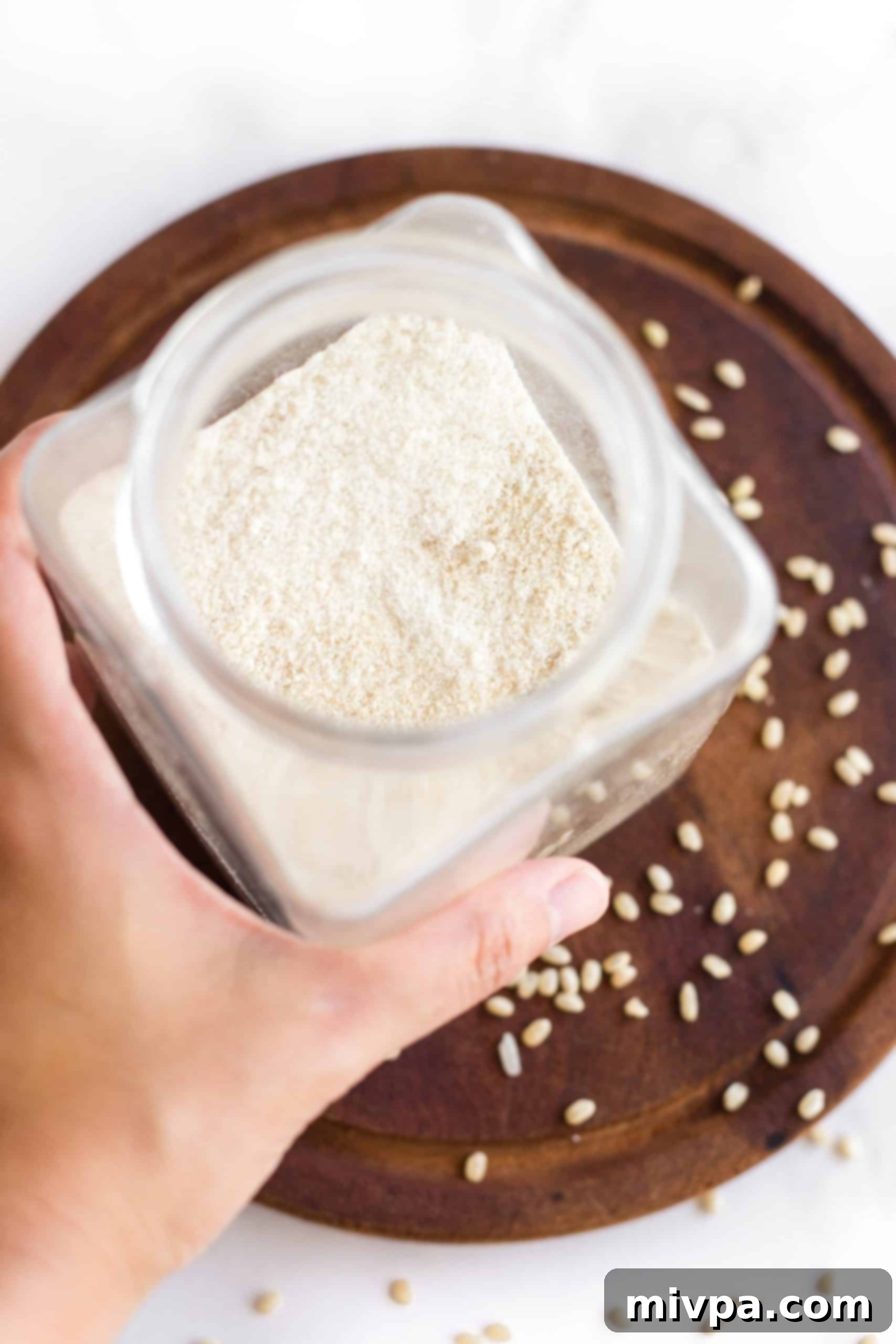 Hand holding a jar of homemade brown rice flour.