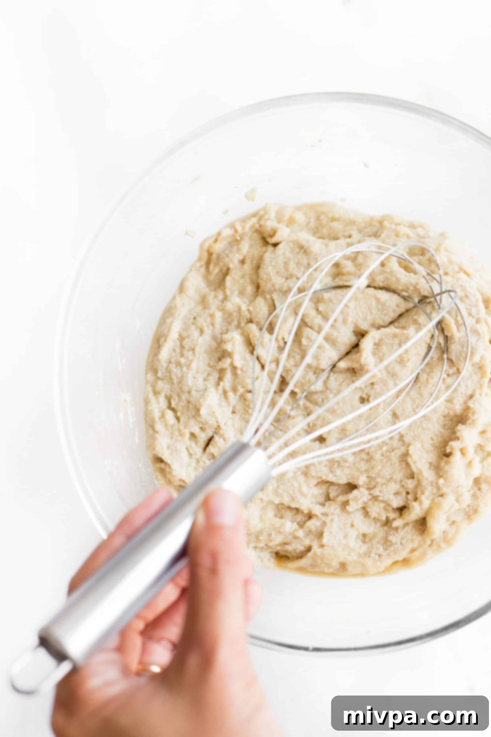 Mixing brown rice bread dough in a glass bowl.