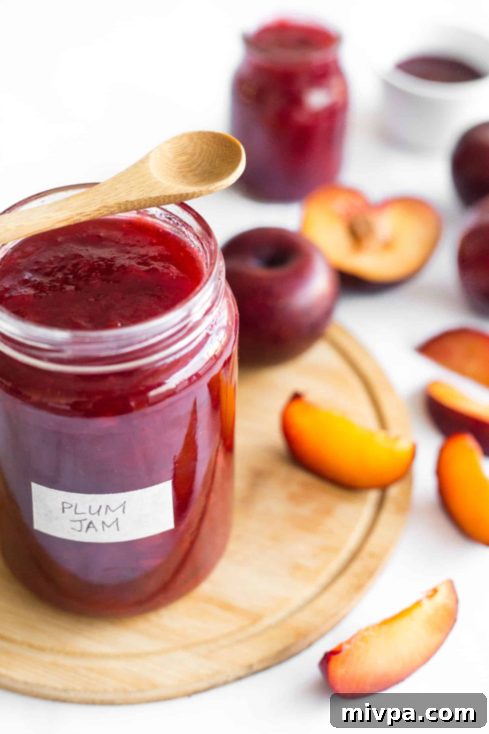 Easy Plum Jam Recipe (Gluten-Free, Vegan, Pectin-Free) A beautifully sealed jar of homemade red plum jelly resting on a wooden board, showcasing the finished product, ready for the pantry.