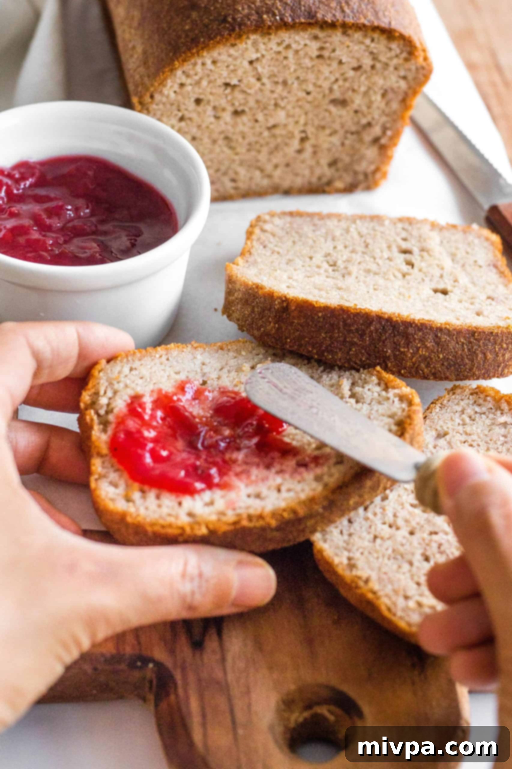 Easy Plum Jam Recipe (No Pectin) A hand spreading generous dollops of luscious plum jam onto a slice of freshly baked bread, a perfect breakfast treat.