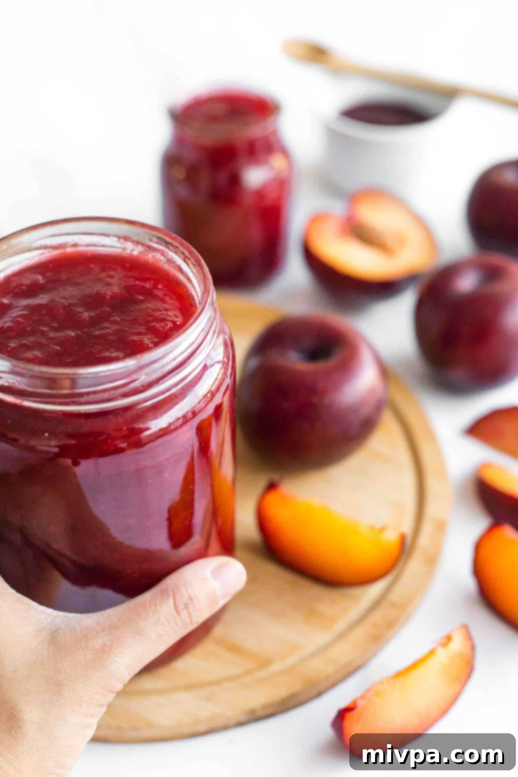 Easy Plum Jam Recipe (No Pectin) A hand holding a perfectly sealed jar of easy plum jam, showcased on a rustic wooden board, ready for storage or gifting.