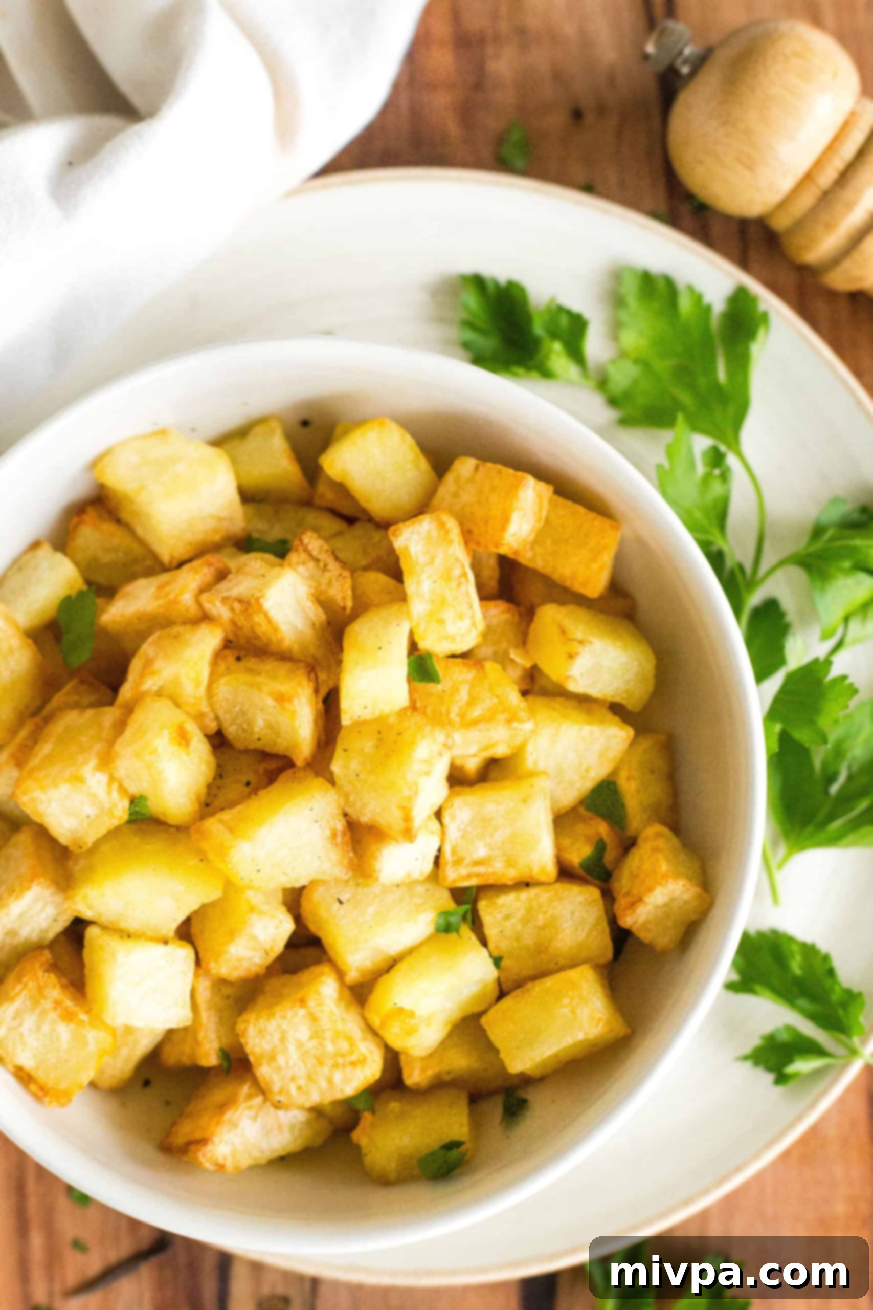 Close up shot of air fryer diced potatoes and parsley on a wooden board.