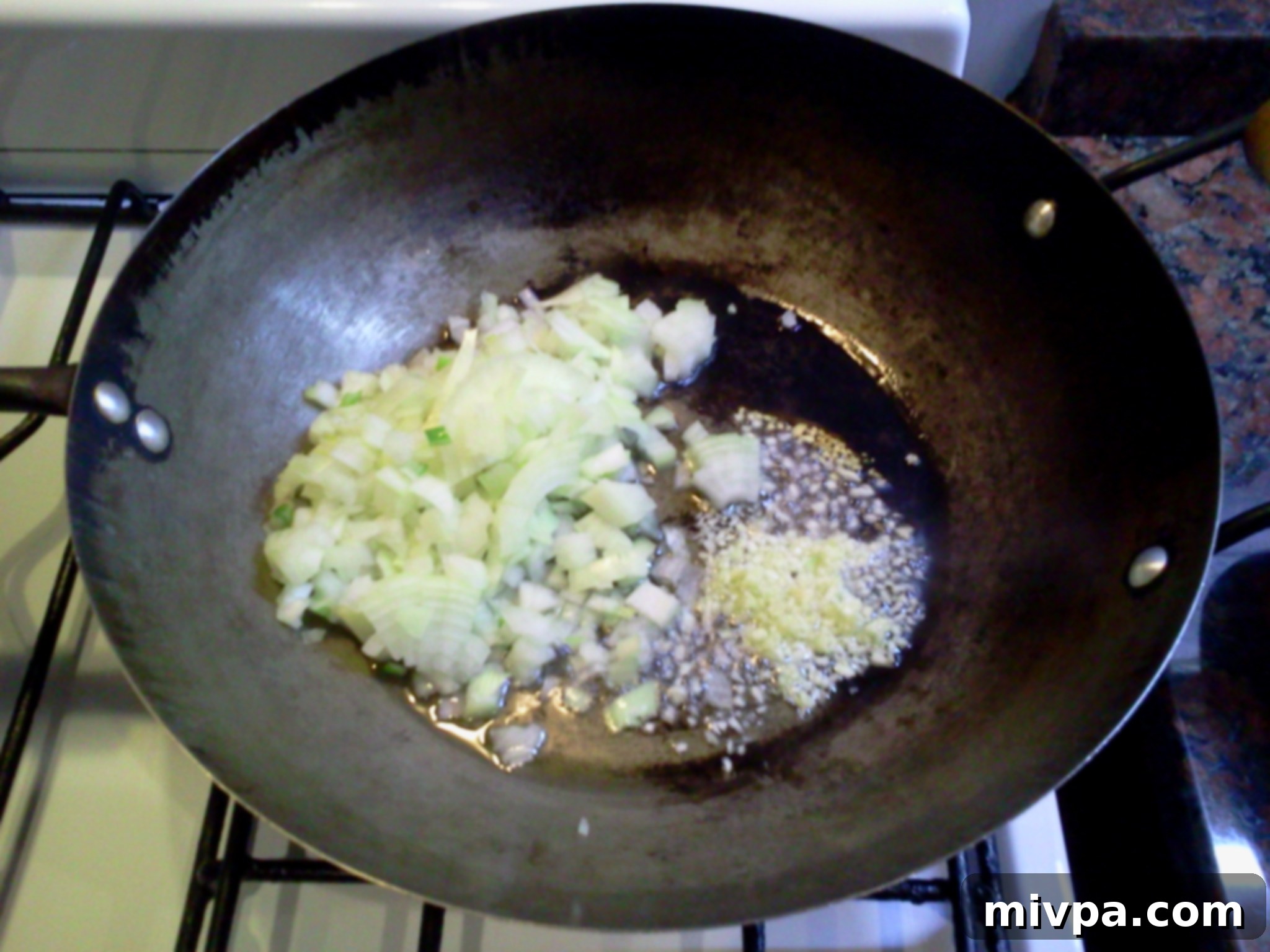 Chopped onions and minced garlic are being sautéed in a hot wok, forming the aromatic base for the risotto.