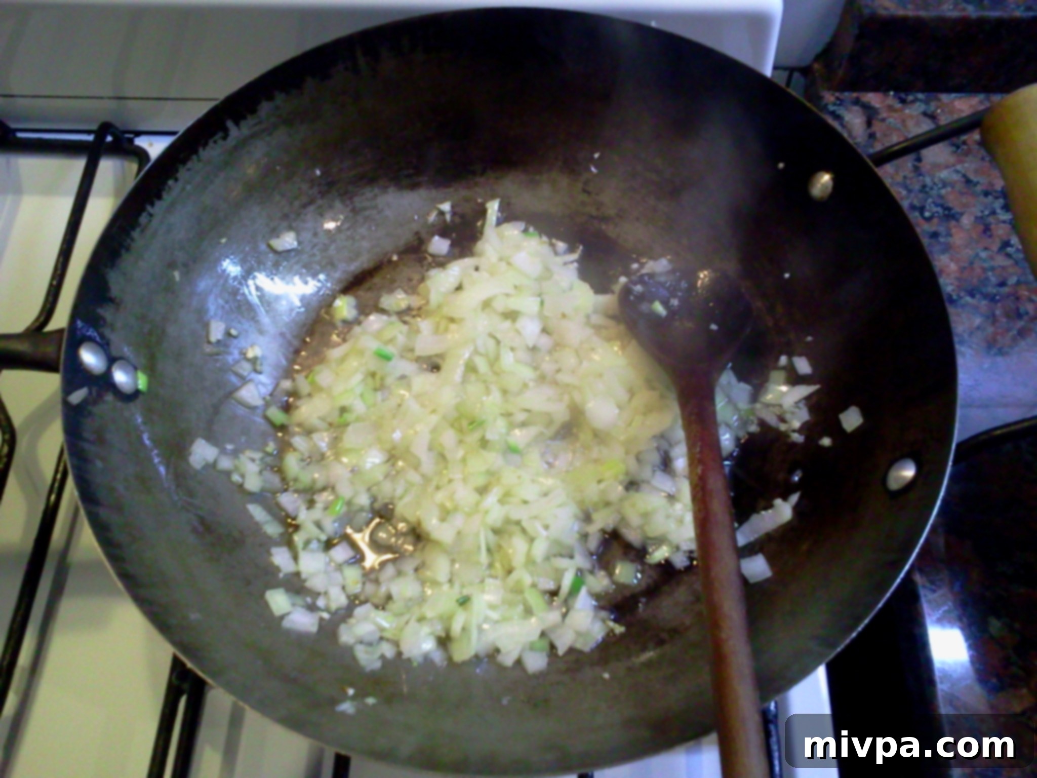 Close-up of finely chopped onions in a wok, having turned translucent and softened during sautéing.