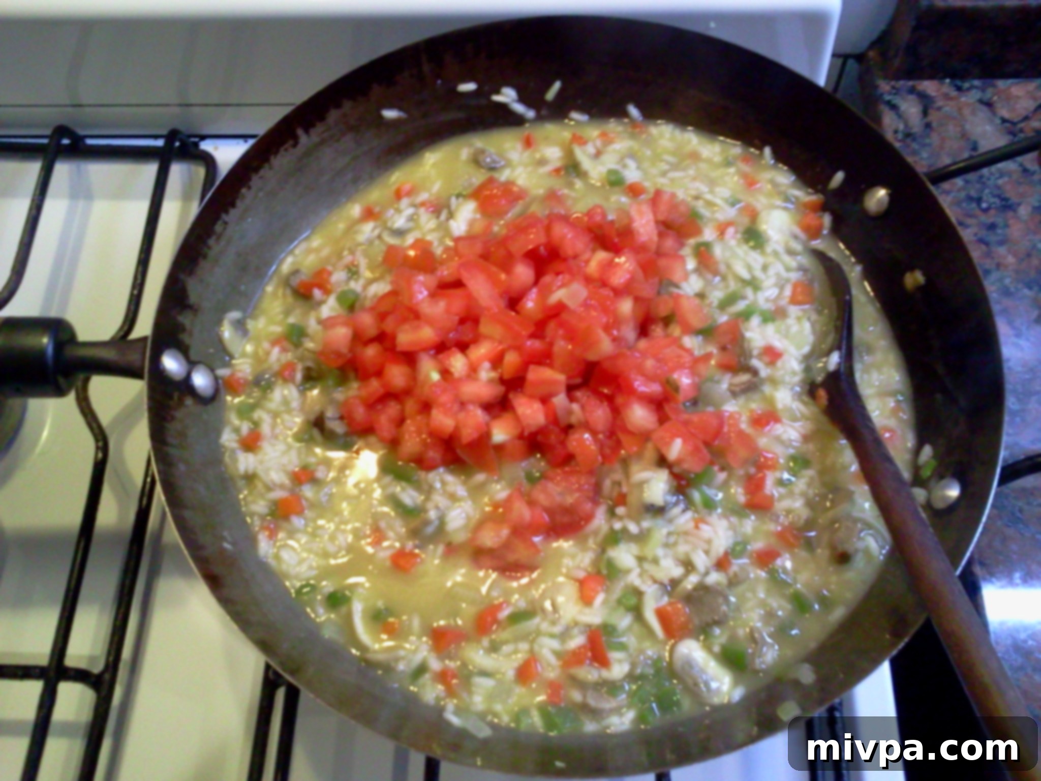 Diced tomatoes, salt, and pepper are being stirred into the almost-finished creamy risotto.