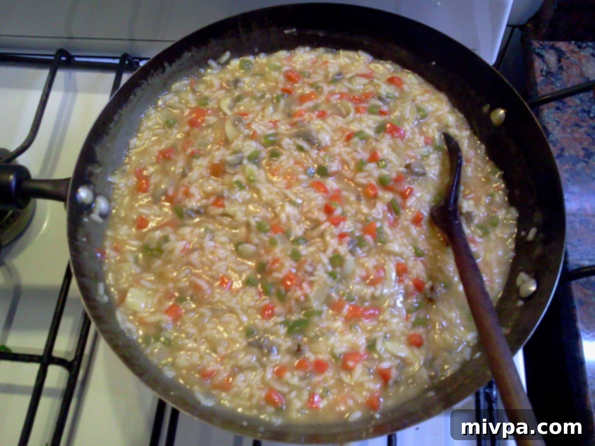 Close-up of freshly cooked, creamy risotto with visible vegetable pieces, ready to be served.