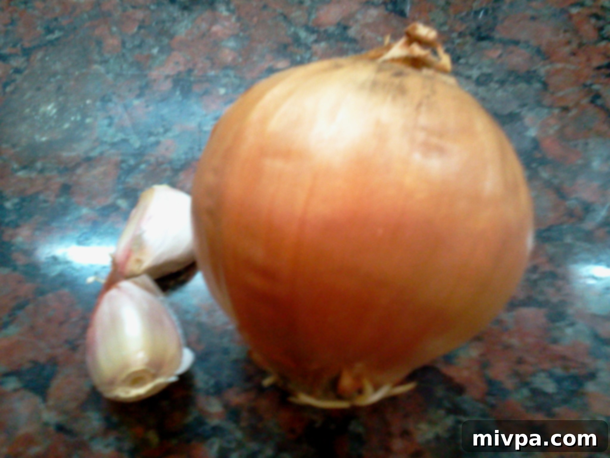 Whole onions and cloves of garlic on a chopping board, ready to be prepared for the risotto base.