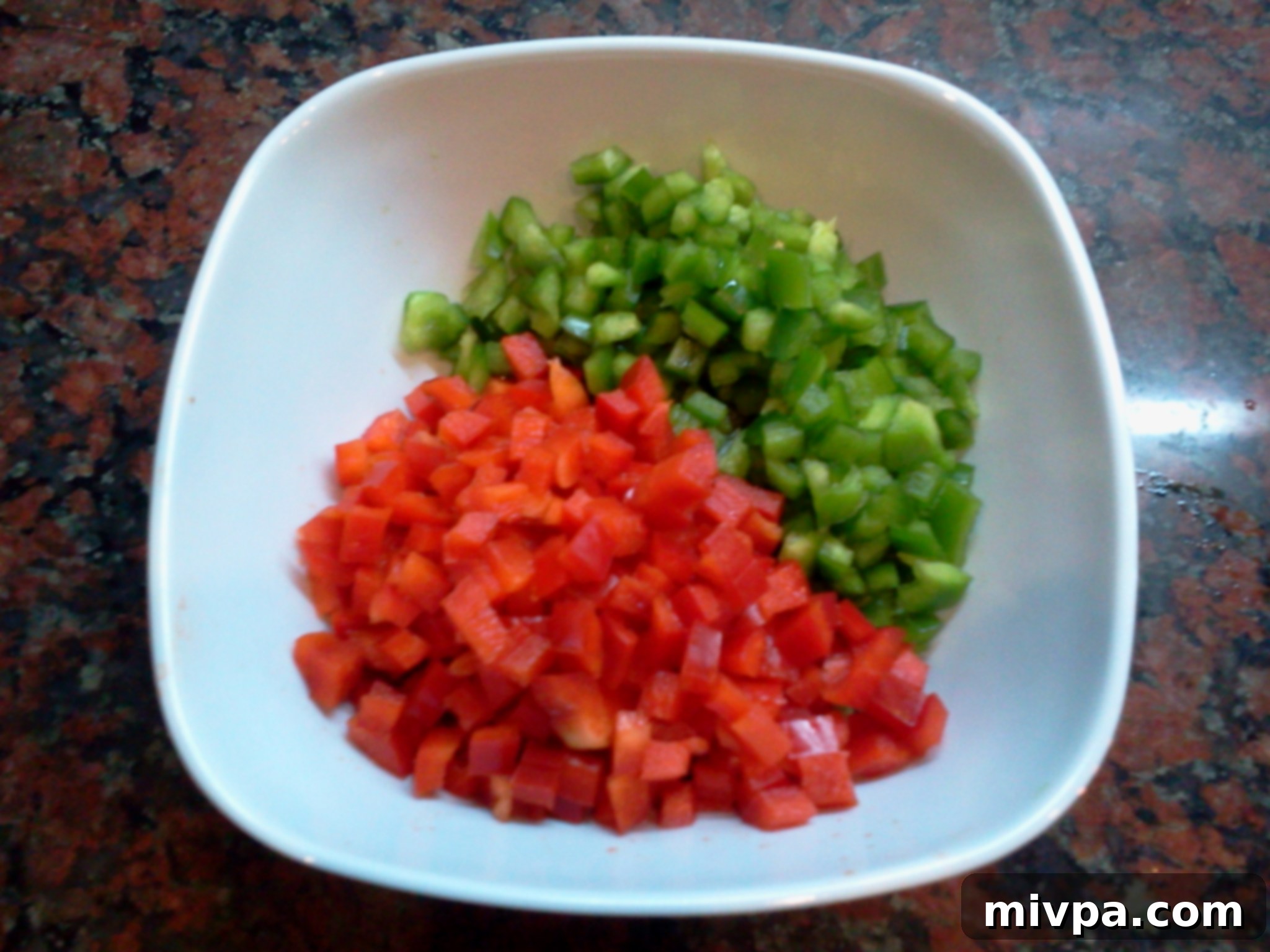 A colorful mixture of finely diced red and green bell peppers, ready to be added to the wok.