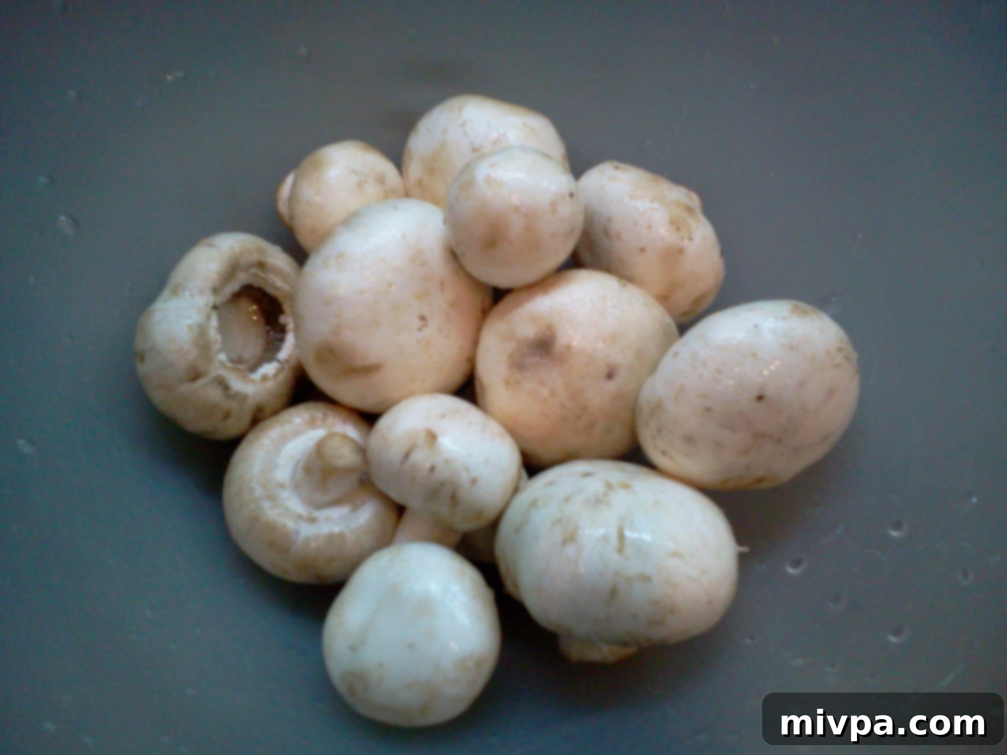 A generous pile of fresh, whole button mushrooms, clean and ready for slicing.