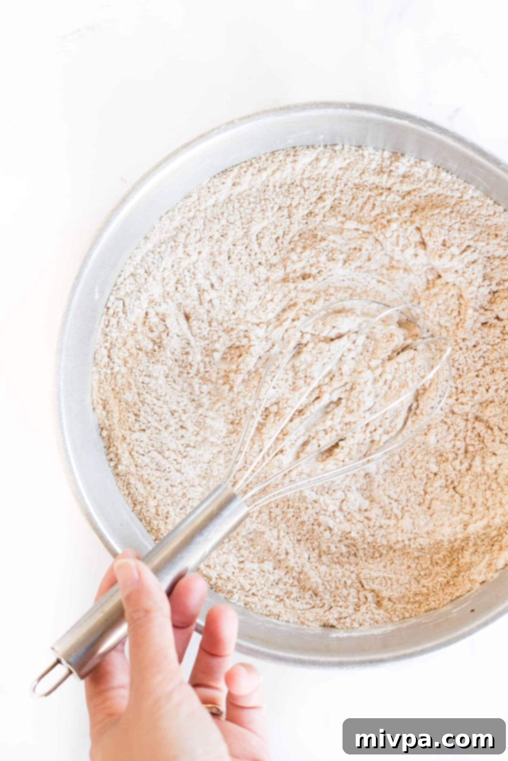 Whisking dry ingredients in a metal bowl.
