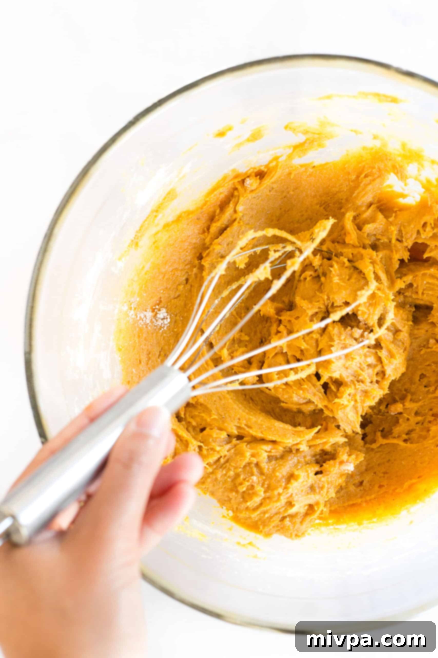 Mixing pumpkin cookie dough in a glass bowl.