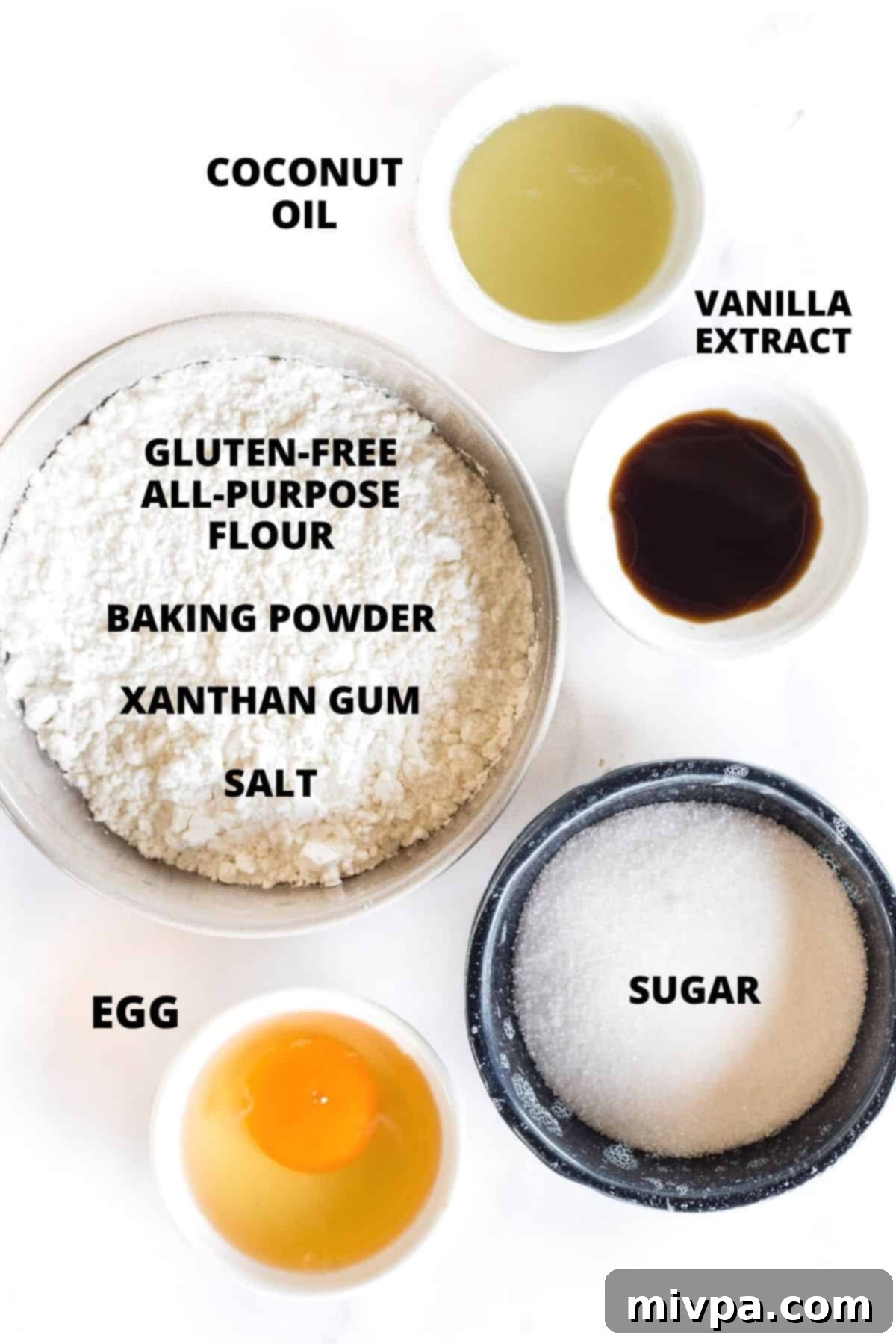All the necessary ingredients for gluten-free sugar cookies recipe neatly laid out on a white board.