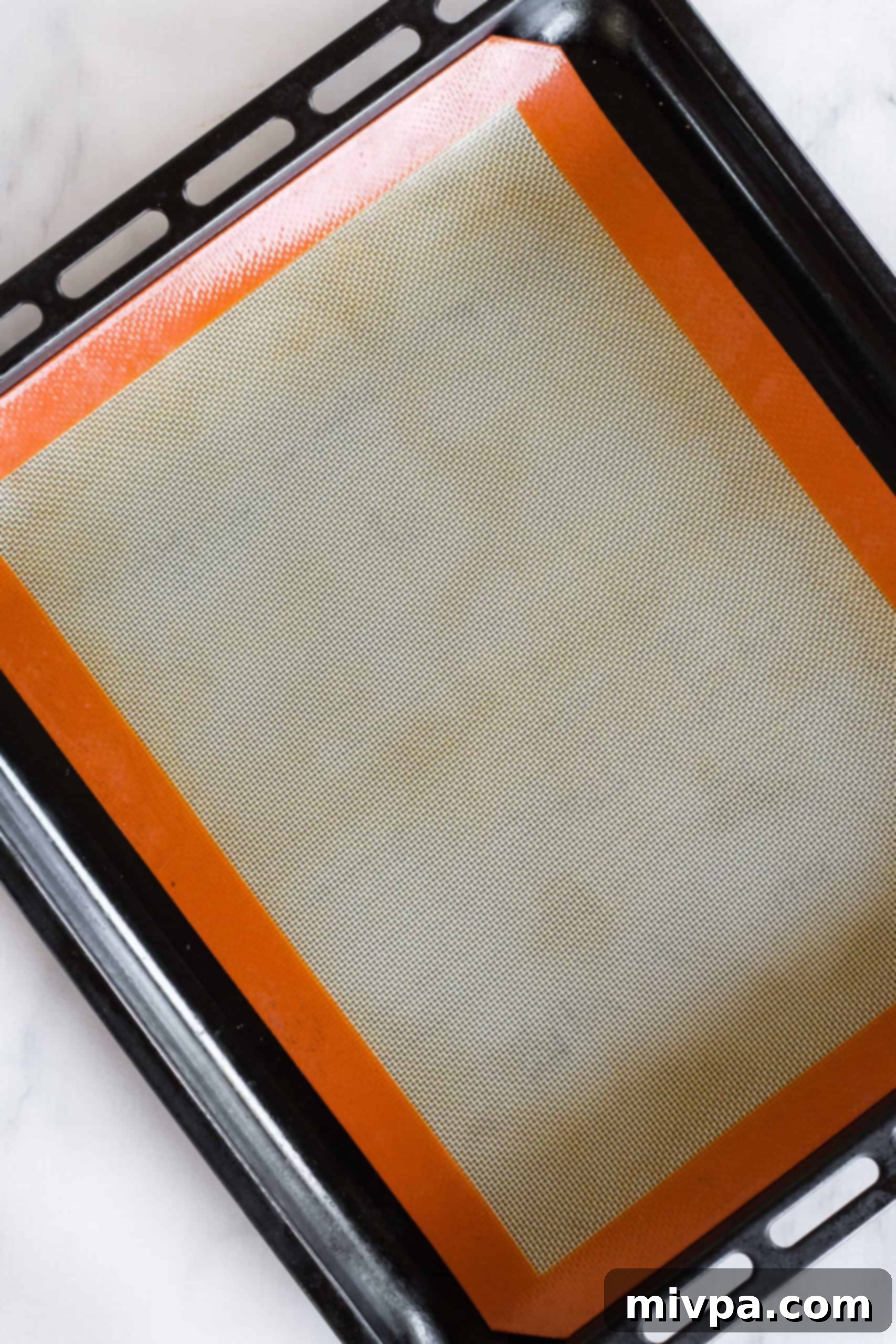 A baking sheet perfectly lined with a silpat, ready for cookie dough.