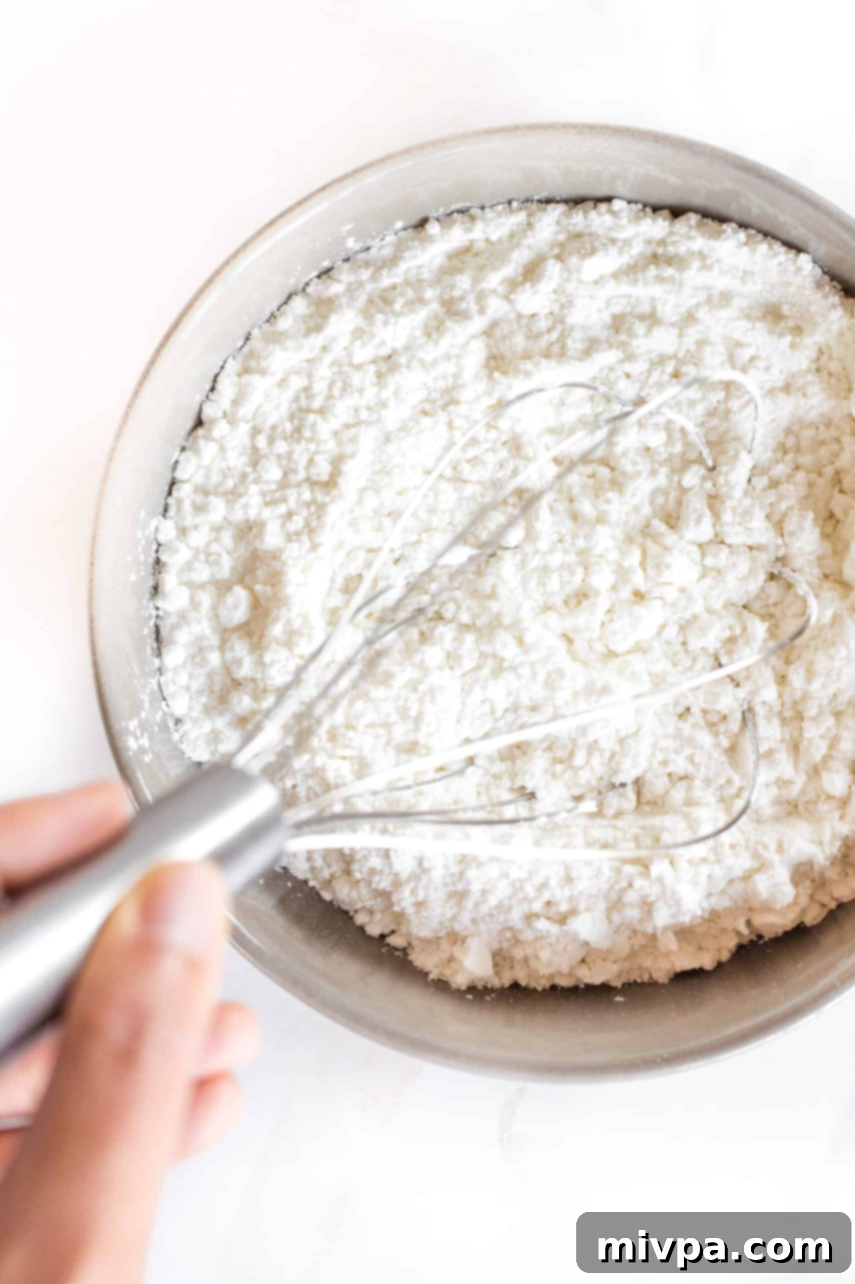 Whisking gluten-free flour mixture in a grey bowl.
