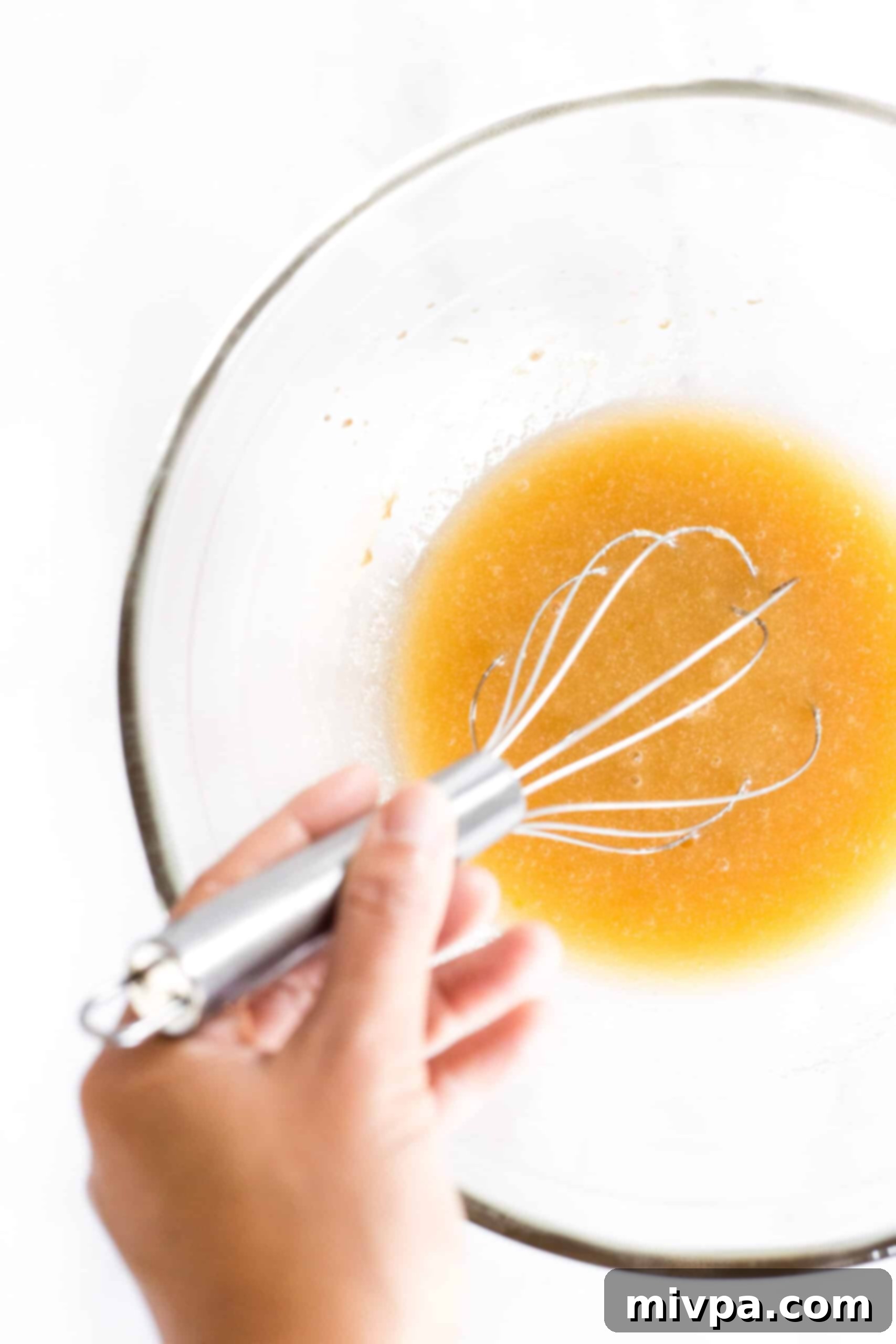Gluten Dairy Free Sugar Cookies A light-brown liquid mixture, comprising egg and vanilla, being whisked to smooth perfection in a bowl.