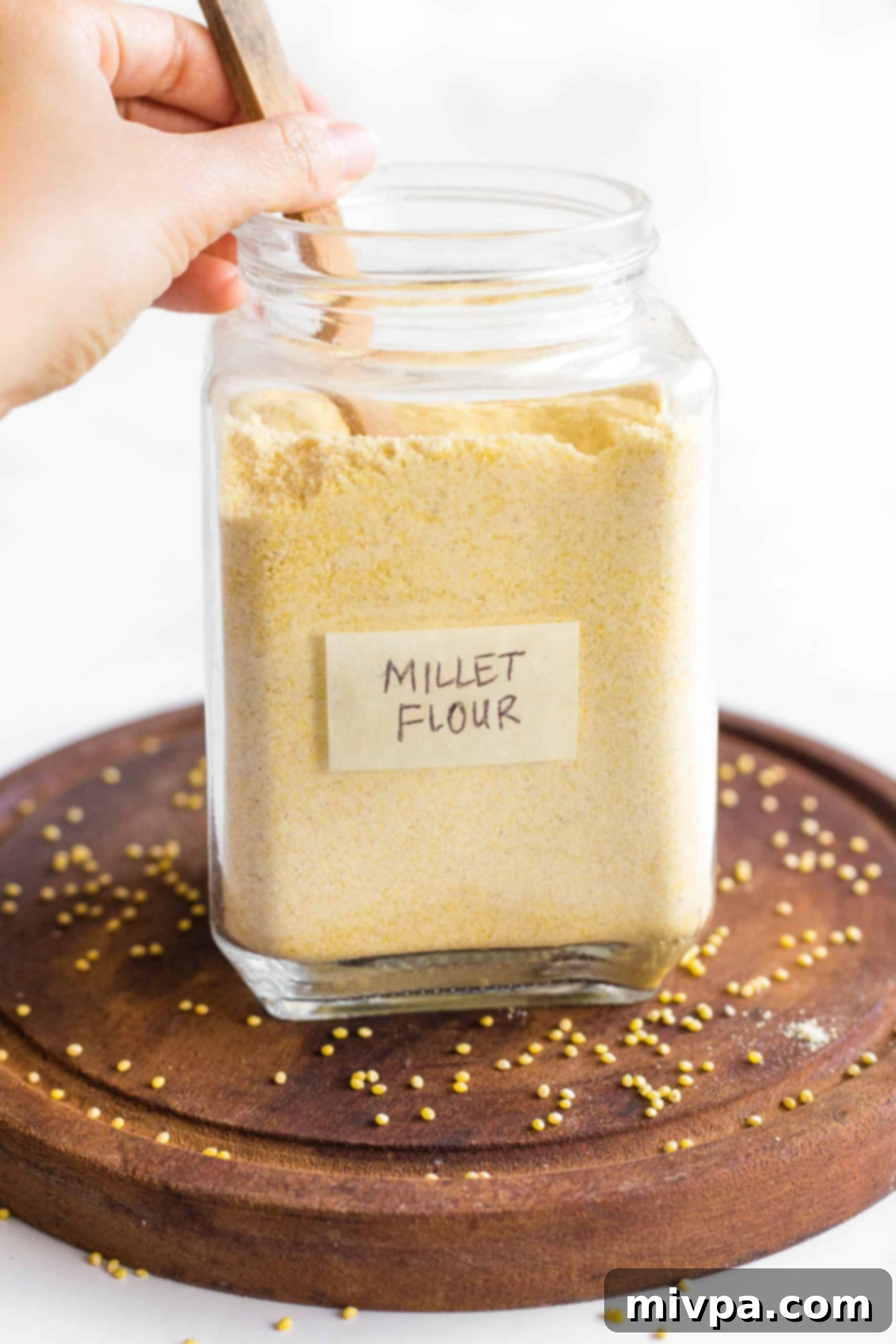 Stirring homemade millet flour in a jar.